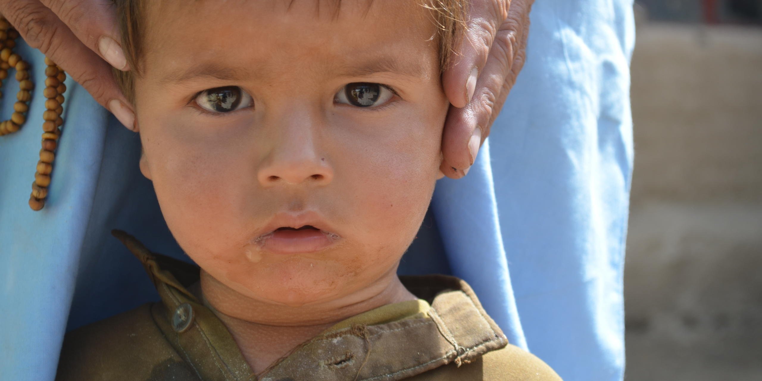 Balbal is holding his son while explaining the situation of his shelter to NRC staff. Balbal 40 is a Pakistani Refugee currently living in Khost Province in a shelter provided by NRC May 2016. Photo: Nisar Ahmad/NRC