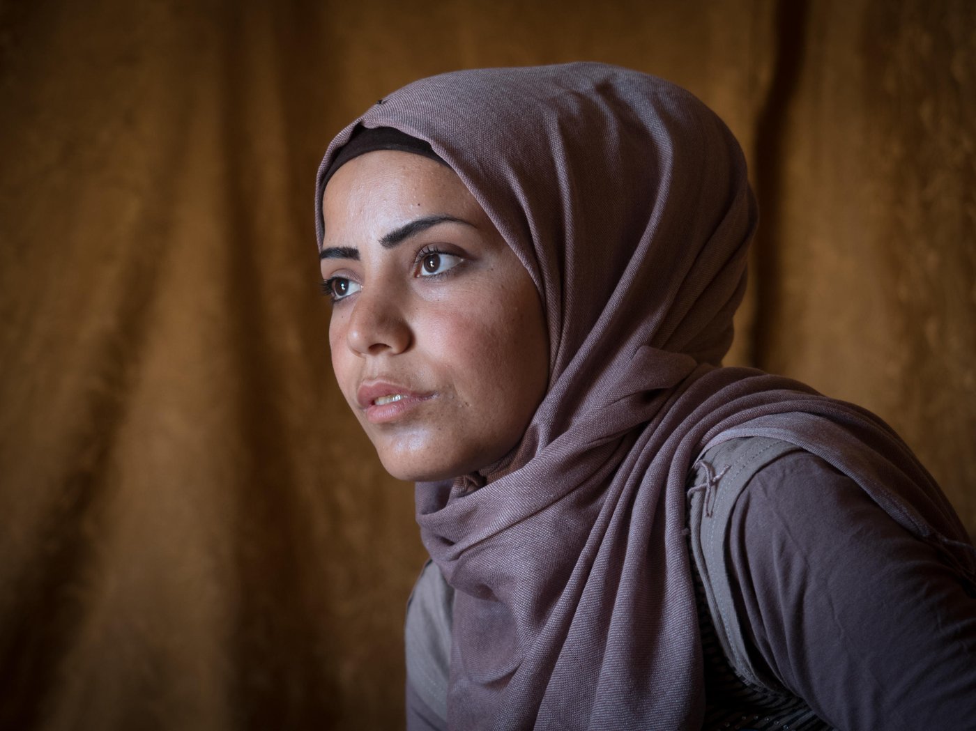 This is Samar. A 20-year-old girl from Idlib in northern Syria. In 2012, she escaped the war in Syria and fled to safety in Lebanon with her family. She now lives in a tent in an Informal Tented Settlement (ITS) in the Bekaa valley with her parents and five siblings. “My family and I left Syria because of the fighting and to save the children and remain alive. I felt sad and it was painful to leave my country, my friends, and relatives”, says Samar.
“When I was younger I dreamt of becoming a lawyer but after I fled from Syria this dream was crushed. I am the breadwinner of the family now, so I can't tell them I want to pursue my dream.” Instead of studying in University she is spending six hours a day, six days a week, doing manual labour in agriculture in exchange for living for free on the land of the farmer. Samar and her sister are the breadwinners of the family of eight since her father is unable to work because of his poor health. The main income is from the food allowance from the World Food Programme and also UNHCR CASH programme.
“I worry a lot about my father because of his health condition. I worry about my grandma who is still in Syria. I worry about not being able to renew my residency permit. I worry about the situation in Syria. I worry about my friends in Syria because they are far away from me.”
The war did not only crush her dream of becoming a lawyer, it also stole the love of her life, Said. The man she was about to get engaged to. The love of her life. “I had pictured my life with this man to be very beautiful. Any girl would have dreamed about it. He had a good personality, he was elegant. Every time when I used to see him I felt true happiness.” Said got killed in an explosion. “I feel a huge sorrow. The first two years were very difficult for me. I couldn't accept that it happened,” Samar says quietly. “At first when I think about him, to our memories, I feel happiness. But then, I feel sorrow because this is something that I lost, he is gone. After Said died, I don't trust anymore, I haven't been able to believe in love anymore.”
Despite her worries and her sorrow Samar has a drive in her to make the future better. “I am always optimistic for the future, I will never stop my optimism,” she smiles. “Said, may his soul rest in peace, used to love me because I was always an optimist. Life has to continue no matter what and he never liked to see me sad. He loved to see the smile on my face and not that I would be depressed.”
So, Samar uses her optimism and drive to make life better for her family and the ones living in her ITS. She is an IFP (information focal point) for NRC. “I help people with hygiene promotion practices, I give them awareness session, and I encourage them that we together should help out to collect garbage to prevent diseases. If a fire breaks out, I put it down. If someone hurt themselves I support with first aid. I check the latrines to make sure they are clean. I give the children hygiene promotion session about how to wash their hands. Also, if parents want to register their children in school I help them. If someone needs to get to the hospital I support them. If someone wants to do birth registration I help them talk to the lawyers,” explains Samar. In addition to this, she also teaches a young girl in the ITS to read and write.
Samar dreams of moving back home to Idlib. “Syria was very beautiful, anyone would have wished to live there. It was very safe. Boys and girls would be out playing till late nights with no problem. No one would cause them harm. Syrian people were very generous and they had high manners. Life was very beautiful. However, I am afraid that Syria won't return to what it was before.”
Photo: Ingebjørg Kårstad/NRC.