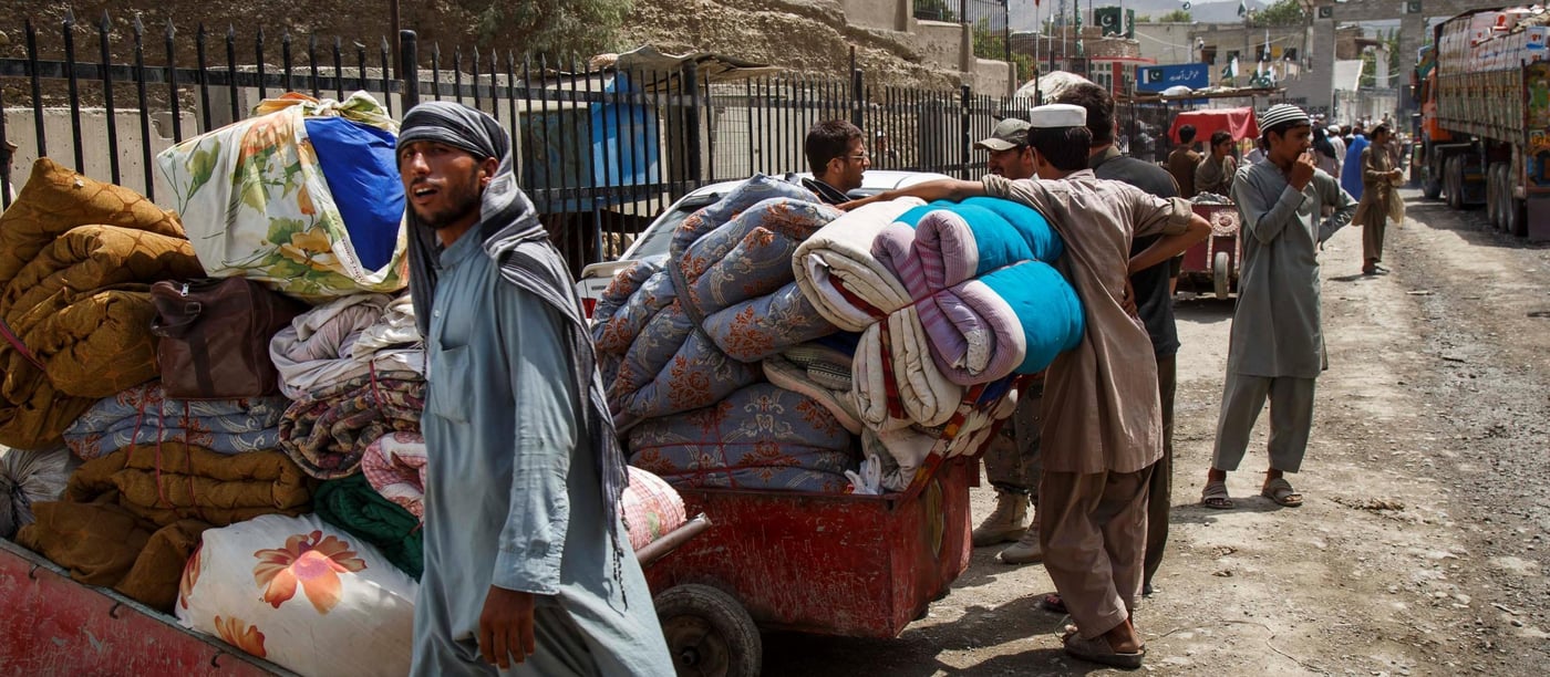 Some undocumented returnee families are too poor to afford lorry rental to transport their goods, and can only move what they can carry on public transport and by foot.  This family brings blankets and clothes through the Pakistan border by wheelbarrows.  Border staff estimate 40-60 returnee families cross without vehicles every day. (Photo: NRC/Jim Huylebroek)