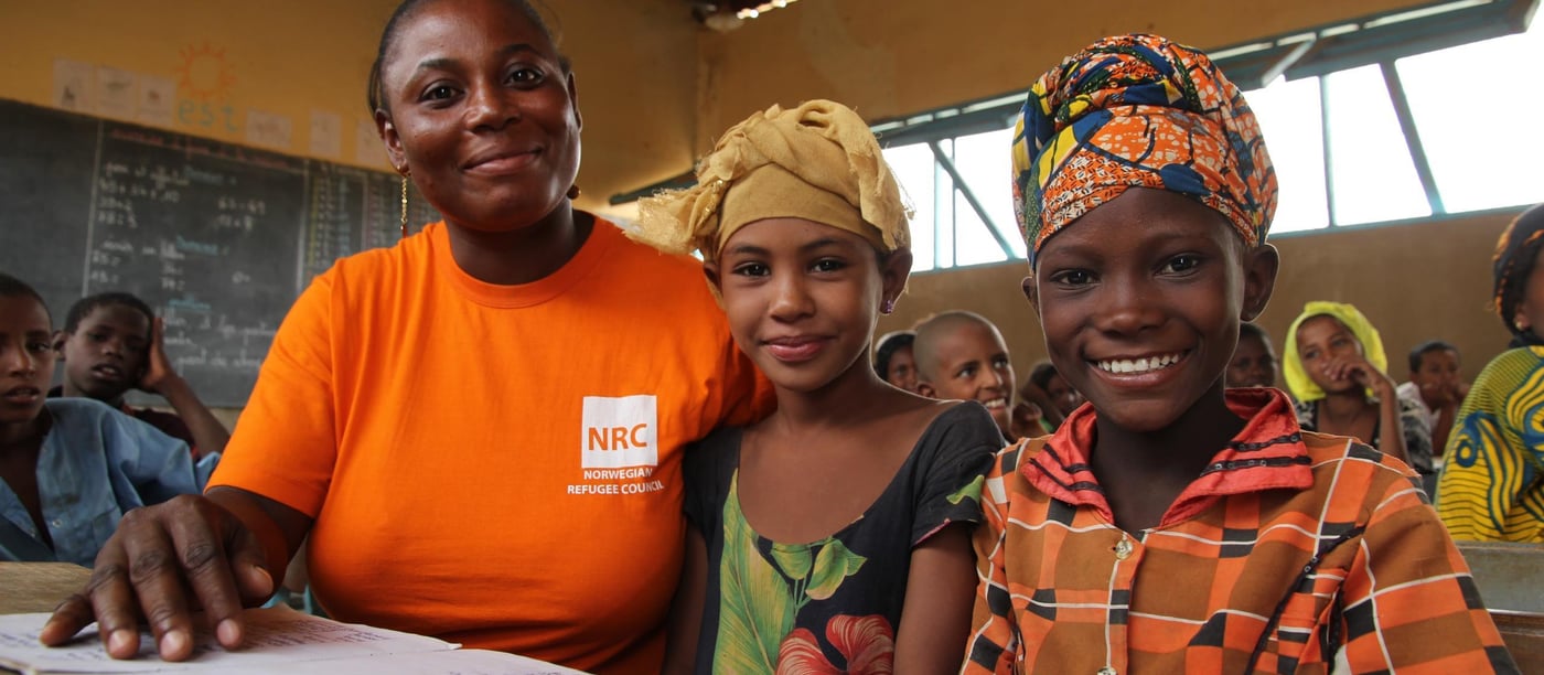 NRC education assistant Diallo Fatimafa  together with Salamate Sambo (12 years old with yellow scarf) and Sada Walette Al Houssein (8 years old with colourful scarf).

 Education:
 NRC has through the years provided different types of education programs. In 2013-2015 NRC ran an education project in the Mentao refugee camp comprising a catch-up programme for children of school going age who have been forced to drop out of school. NRC also had  a YEP program (combining literacy educational and learning crafts) for youths between the ages of 15 to 24 who can no longer make in into the normal school system. 163 pupils completed the catch-up programme while 105 youths completed the YEP programme   

Now NRC is providing education for smaller children in the Goudebo camp; Ecole Primaire de Goudebo has between 800 and 900 pupils aged from 6 to 12 years, divided in six grades. The number of pupils differs with families trying to return to their country of origin. Return programme is facilitated by UNHCR.

Most of the pupils are refugees, but the school also has some pupils from the host community.

There are 6 grades at the school. In the first two years (CP 1 and CP 2), there are two teachers in each class. Because the school language is French, and many of the refugee children do only speak local Tuareg dialects, they need help for translation to be able to follow the education. (Official schools in Mali is also teaching in French)

NRC target that 50% of all pupils should be girls is met in the vast majority of the classrooms. The age of the children in each class differs. Most of the children arriving in the camp have never gone to school before, so they have to start in the basic class regardless of their age. 

Most of the pupils have books to write in, but in a few classes the pupils still uses small wooden boards and chalk.

Photo: NRC/Ingrid Prestetun