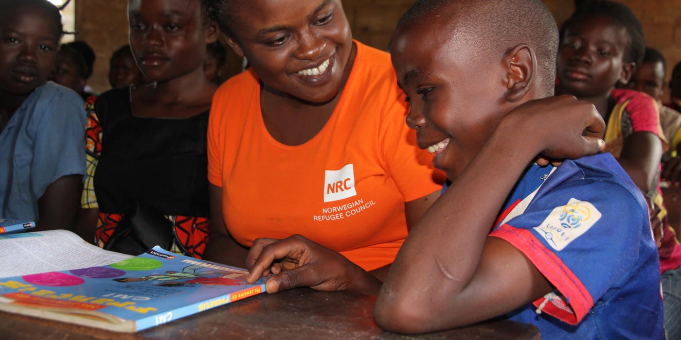 NRC Area manager Aimee Ndakala together with children attending the Gbagaga school in Carnot. The school has more than 500 pupils, but only three classrooms. Therefore the grades are sitting together; 1st and 2nd, 3rd and 4th, 5th and 6th grade. To educate as many as possible at the school, they have two shifts per day, in the morning and in the afternoon. NRC is now (May 2015) building a new school besides the old one, to increase capacity and because the old school building is at risk of falling apart, due to decades of erosion and building material of low quality. The children from 6 to 17 years learn to read, write and mathematics. 

Information about Aimee:
Aimee NDAKALA MPALA - Area Manager Carnot (Central African republic)
Nationality: Congolese
Been working 11 months from NRC

Background:  She did medicine and sociology science and she is proudly and happily mother of 4 children and her home is in Kinshasa.  She used to live in Goma, but because of insecurity, she decided to move in Kinshasa last year. She sees her family every 8 weeks.

Her background: When the war broke in Democratic Republic of Congo in 1997, she was a student in Bukavu. She fled from Bukavu to Kindu , it is more than 500 km. She is grateful for the assistance she received from very poor people in villages. But at this time she was struggling with the prospect of herself not completing her studies if peace does not return, but also she had no news about my family for more than 2 months.

Why working for NRC? She was displaced and she knows what life is like as displaced person.  She works for NRC to support those who are currently in a displacement situation to overcome.

Her motivation:  As a displaced person in the past, she would like to be part of the solution, to be an example of success. NRC gives her the opportunity to talk to displaced persons to not give up, there always hope.

She started up the NRC Carnot office last year:  she came in Carnot on July 2014 and handed over with the emergency team. At this time she had no staff no office neither a house just two project funded by the common humanitarian fund and the Norwegian Ministry of foreign affairs. A start by recruiting program officers and coordinators, but also the finance and logistics staff.  They began by an assessment to select villagers where they should work; they did another assessment to understand the displaced people challenges in the area. Aimee used to live in the catholic priest compound with no internet and limited access to safe water and electricity. Today she is so glad, they have a NRC office, a NRC guest house with all the facilities and more than 50 national and international staff.

NRC Carnot helps children come back to school and they manage to make displaced people life more secure. They began the work on land and property, as displaced people lost their houses, their shelter program is rebuilding some houses. She is so happy to work with very talented and brilliant people. There are more male than female staff in the office. A normal working day for her is 10 hours in the office of field trying to find solution and a hub of security for displaced persons.

Education is the biggest activity in NRC Carnot because it is a human right as well as a component of peacebuilding. Through education they are introducing a culture of tolerance and conflict resolution between children and youth coming from opposing communities.  YEP senter is a great example on this where they are opening the door to the community safety and economic development 

General challenges regarding schools in CAR:  overcrowded classes with poorly trained teachers. Also  few female teachers are also characteristic of most of school in CAR.

Quotes from Aimee: “Education is essential to prepare the displaced people to return as their situation is temporary but also to rebuild their life. Education is important because it can bring people from different places together; education can be a tool for protection. I am sure that through our education program we are impacting children but also their families and communities as well”.

The issue of discrimination and safety for displaced people in Central Africa Republic present a big challenge for her work. 

Quotes from Aimee: “Being a woman in Africa and having such position in a country where gender based violence is common is not easy! You must challenge yourself every day, you must demonstrate every day that you can handle the work. Lack of qualified staff and more particularly qualified women is a big challenge for my work”.

She hopes that displaced will return in theirs villages and have right to movement. She hopes that the communities will live together in peace
Photos NRC / Ingrid Prestetun