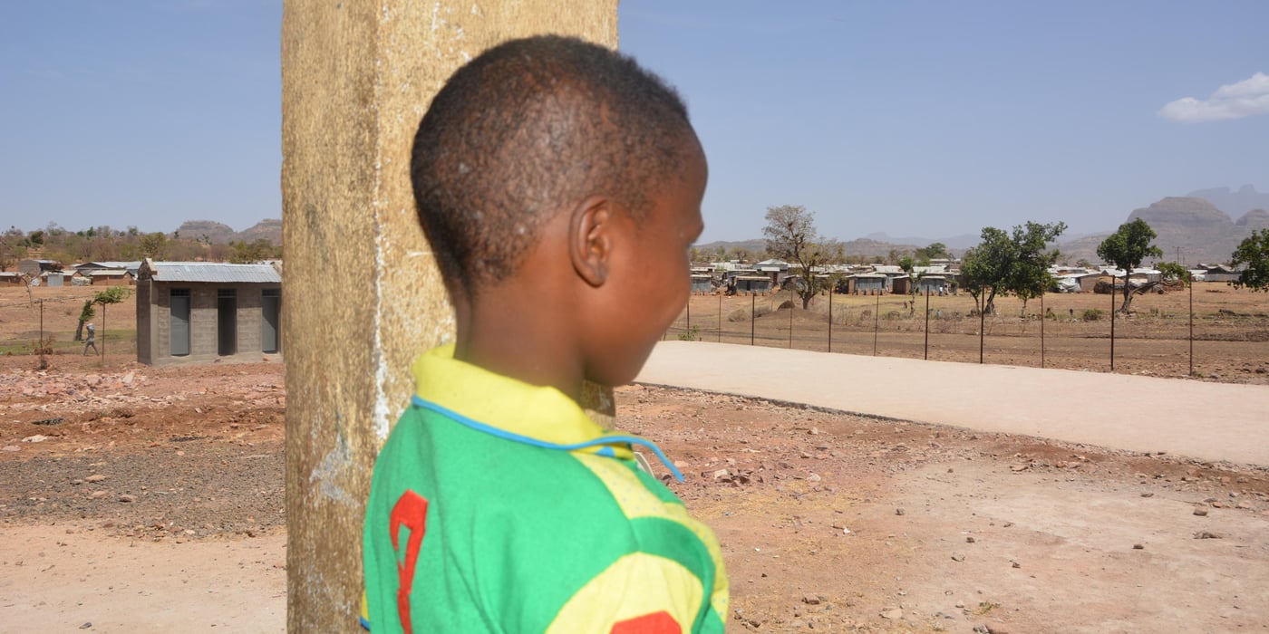 11 year old Eritrean refugee at NRCs child friendly space in Adi Harush, Shire
Eleven year old Henok risked his life for the chance of giving his family a better future. This is his story.
An eleven year old boy is supposed to go to school, come back after and ask his mother for something to eat, and then rush outside to play with his friends. An eleven year old is supposed to leave all the worries of life to his mom and dad. An eleven year old is supposed to smile instead of spending his days and nights deep in thoughts. He might help his mother with house chores or collect firewood for dinner. He might not be too young to attend to the goats and cows in the meadow, but he is way too young to even dream of risking his life to change his family’s life. Unfortunately, Eritrean boys like eleven year old Henok take a big risk by crossing borders to come to Ethiopia, in the hope that they will get a chance of resettlement or cross the desert and ocean to reach the western world.
Henok Mehari is only eleven but already attempting to carry the world on his shoulders. All he thinks about is what his life will be like in the future when he goes “out” of the country. “Out” is the word everyone uses in the Ethiopian refugee camp to refer to European and other western countries. Henok, like many other young Eritreans who have sought refuge in Ethiopia, is focused on going “out” no matter what it takes. He knows very little about the risks involved or the amount of money he needs to pay to cross borders and reach his dream destination.
Henok grew up looking at young boys and girls walk past the meadow where looked after the goats and other animals, on their way to crossing the border to Ethiopia. He heard talk in the neighbourhood of going to European countries and how the best route is to first go to Ethiopia.
One day, Henok saw a group of youngsters walking towards the border and followed them without thinking. The young shepherd left home without his mother’s knowledge.
It has been a year since he came to Adi Harush refugee camp in the Tigray region of Ethiopia. He has no regrets, but he misses his home, his mom and his brother every second.
“I didn’t tell my mother because I was afraid she might say no. She will be disappointed for a while, but she will be OK knowing that I am going to a rich country to help her and my brother,” Henok says without hesitation.
Even though he looks young, he seems to analyse the situation around him. “Life is hard in the camp, but I have lived in poverty since childhood, so it doesn’t bother me much,” he says. Henok goes to school in the camp. His favorite subject is science and his other life dream is to become a teacher when he grows up.
Henok likes the group of people he currently lives with. He says it makes him feel like he has all it takes to face the challenges of life. He goes to school and gets assistance from aid organisations like NRC. Still, he is always thinking about going “out” even though he doesn’t have the money or any relatives living in Europe or other western countries that he can rely on for financial support. Henok doesn’t know what will await him in the foreign land or how to get there. All he knows is that other people are doing it and he will not pass the opportunity when it comes his way.
Refugee children in camps
Henok is being taken care of in a community care centre that the Norwegian Refugee Council (NRC) has set up for unaccompanied and separated children in the camp. There are children as young as five in the in the refugee camps of Tigray, Ethiopia. NRC is one of the organisations that provide assistance to these children.
Photo: NRC/Emebet Abdissa