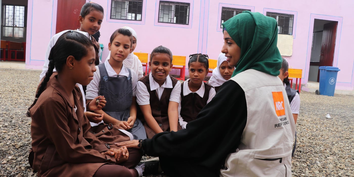 NRC’s Education Assistant in Aden, Malka Mohammed (26), remembers March, 2015 as a time that turned from being a joyful month of celebrations and weddings into a living nightmare. She was working as an English teacher in her home city of Aden when a colleague ran to her classroom, knocked madly on the door and shouted: “They’re attacking the city!”
“We evacuated the school. There was a lot of confusion. There was shooting everywhere,” she recounts. Over the next few weeks, it got worse and the fighting drew closer to Malka’s home.
“Every day, I heard stories of how people had been killed, and I saw the remains of destroyed buildings. It scared me to death. I was particularly afraid during those early morning hours when the airstrikes would begin.” She remembers one day waking up to the screams of the little girl next door. “I ran out to the street without wearing my abaya or even a scarf on my head. I was running like mad and the street was full of people. It felt like the end of the world, the sky was covered in red lightening.”
Malka and her mother ran as fast as they could. They eventually reached a house at which they felt safe and were welcomed in by the people living there. They stayed until the next morning.
A stranger helped Malka that day. Now, she is helping others.
As an EducationAssistant in southern Yemen, her job is to make sure children living in conflict can still access school. Through our education work, we rehabilitate and rebuild schools destroyed by shelling and other attacks, we distribute school materials, teach teachers and organise school meals.
“We cannot lose education in Yemen. If we lose education, we can lose a whole generation,” she says, and continues: “Education is so important, and that’s why we try to support young Yemenis to create a better life for themselves, and a future.”
Photo: