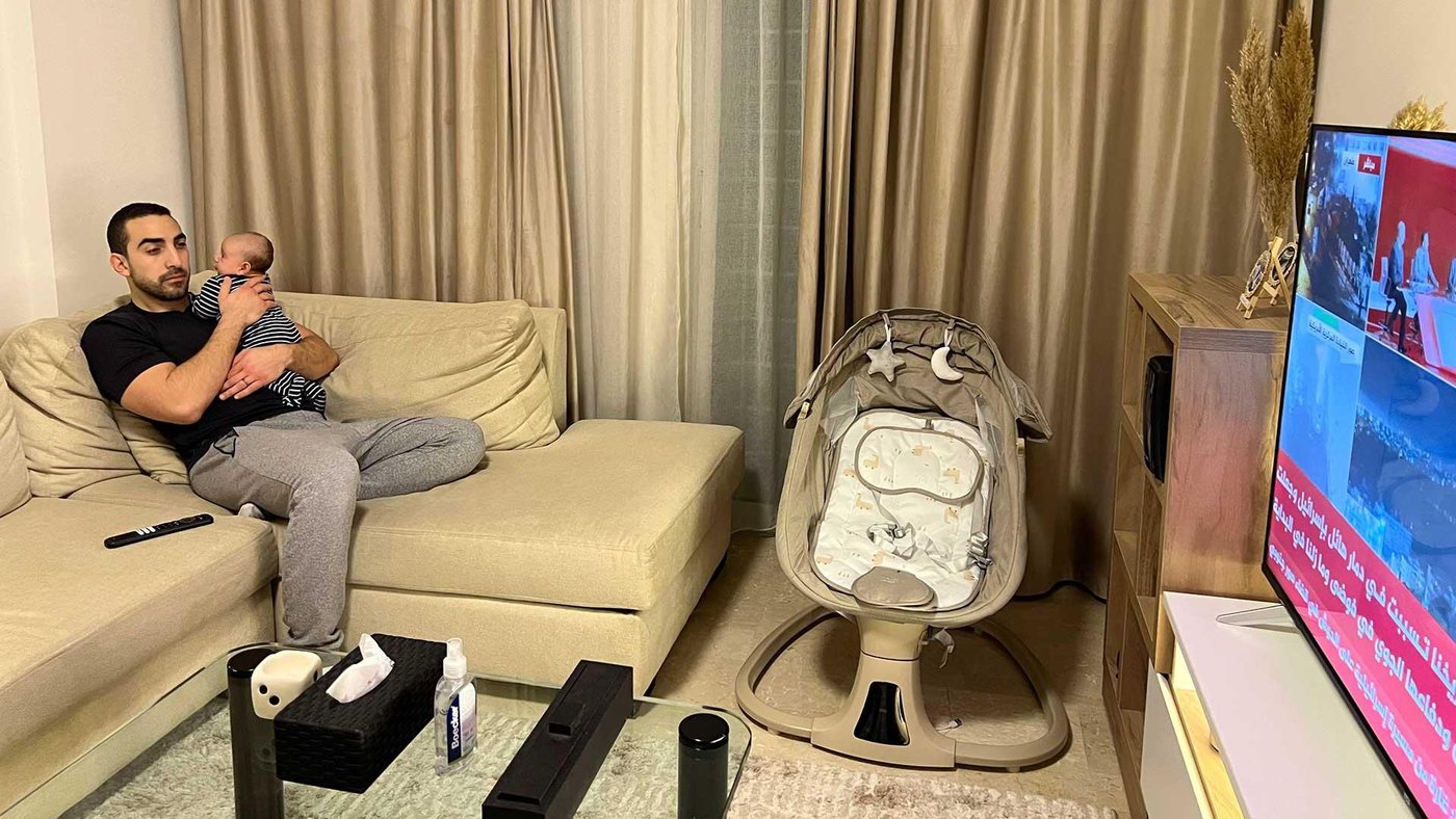 A father and his baby, watching the news at home