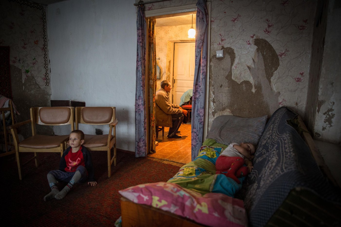 Illia, 5, is watching cartoons on TV while his baby sister Aryna, 2, is having her afternoon nap on the sofa. In the small kitchen their father Viktor is having a small rest from his work outside.
Background story:
Liliia Poturoieva is 39. She has experienced terrible events that completely changed the life of herself and her large family and left an indelible mark on everyone's soul. She lives in the frontline village of Verkhnia Vilkhova in Stanytsia Luhanska district, Luhansk region.
Liliia has six children. The oldest is Oleksandr. He is 20. He lives separately from his parents and earns his own living. Ihor is 12. He is a shy and calm schoolboy, always ready to help parents with the housework. Her eldest daughter Iryna is 10. She is a schoolgirl and mother's main housekeeper. She cooks and looks after younger children. Yana is 7. She is a first-grade pupil. She is a cheerful, active and very energetic girl. The children are forced to go to school in a neighboring village 5 kilometers away, since there is simply no school in their village.
Her youngest son Illia,5, and daughter Aryna, 2, are always staying at home with their mother. The family cannot afford a kindergarten for children. Now Liliia is pregnant again. This will be the seventh child in the family. Her husband Viktor helps her to cope with all of them.
Before the conflict, the whole big family lived in a small house with two rooms. There was no work. The main income was child allowances and random earnings from the cows, goats, rabbits and poultry.
“There was no work in the village. There was no opportunity to travel to other settlements to work. We tried to make money by selling milk”.
In February 2015, at midnight, heavy shelling began. Viktor, Liliia's husband, went out into the yard to see the direction of the shots. Suddenly a shell fell near their yard, and the second shell landed 7 meters away from Viktor, who was standing on the house porch. Viktor got a serious shell shock and lost his hearing for a while.
The blast wave knocked out all the windows in the house. Under one of the windows there was a child's bed, where Liliia’s youngest son slept. That night Liliia saved the life of her son with her son.
“When the blast hit, I covered my baby with my own body, and the glass from the broken window hit me in the back”.
The consequences of that shelling are still noticeable. Liliia has problems with her speech. She is stuttering. She is not the only one.
“The children experience anxiety, concentration problems, fears and, as a result, urinary incontinence”.
The house was seriously damaged in the blast. All the windows were broken, the front walls were destroyed and the roof and the foundation were seriously damaged. However, Liliia and her family did not dare to leave because it was too risky to leave the house unattended. They tried to repair the house on their own. They covered the broken windows with plastic wrap. They even had to spend their nights in the basement because it was the warmest and the safest place in their household.There was no help from the local authorities.
“At first I didn’t want to ask for help. I did not believe that anyone would really help us. My husband advised me to go to the NRC office and find out about the Heavy repair project, because he heard that NRC had already helped someone in the village”.
Now the house is in the process of restoration. There is a new slate on the roof. Renovation works on the walls have been completed. Three small rooms for the children have been completed. New windows have been installed and internal works are being carried out now.
“The main thing for me now is that the active phase of the war does not break out again. I am afraid that my house will be destroyed again. After all, we hear the sounds of shots every night”, Liliia says.
Photo: Ingebjørg Kårstad/Norwegian Refugee Council
