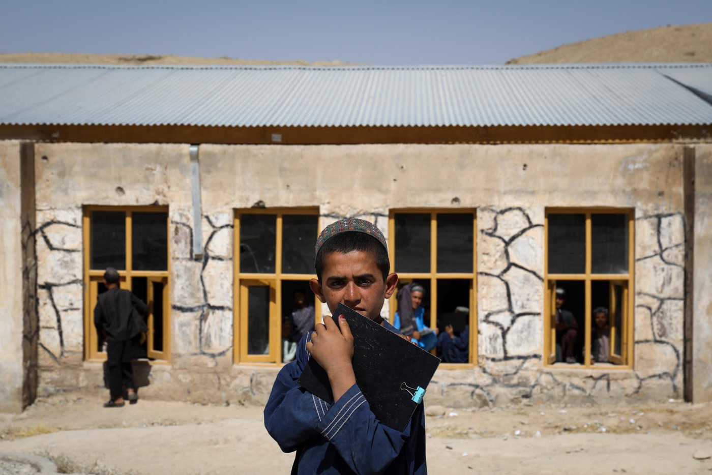 This is Charamgar secondary school some 5KM on the northern side of Trinkot, Uruzgan Province. This school was occupied and used as a checkpoint by the Taliban for almost six months in 2015/16, but the school remain shut for whole academic year. When the the Taliban were moved back and school resumed again, all the roofing, boundary walls and gates were either destroyed or was stolen.
NRC stepped forward and started doing some basic security upgrading to this and some three other schools in and around Trin Kot. The work includes; Iron sheets for the roofing of schools, installing emergency gates, main gates, building boundaries walls, grill work, windows repairing, glasses and blast films for the windows. NRC also established a schools-based Protection Committee (SBPCs) for each school with support and participation of PED, Community shura.
The school activities are closely monitored and checked by the community people, PED and the community has also been accountable to protect the schools from future expected incidents and they are also encouraging the families to get their children to school.
Repairing work and studies continues in this school and currently around 15 staff are teaching some 600 students in two different shifts.
“We feel more safe and secure now after building the boundary walls and installing the gates. Now, we have bigger yard and students can play inside the school building. The boundary is also keeping safe from any attack and flying bullets,” said Nida Mohammad, the Chramgar school principle.
Photo: NRC/Enayatullah Azad