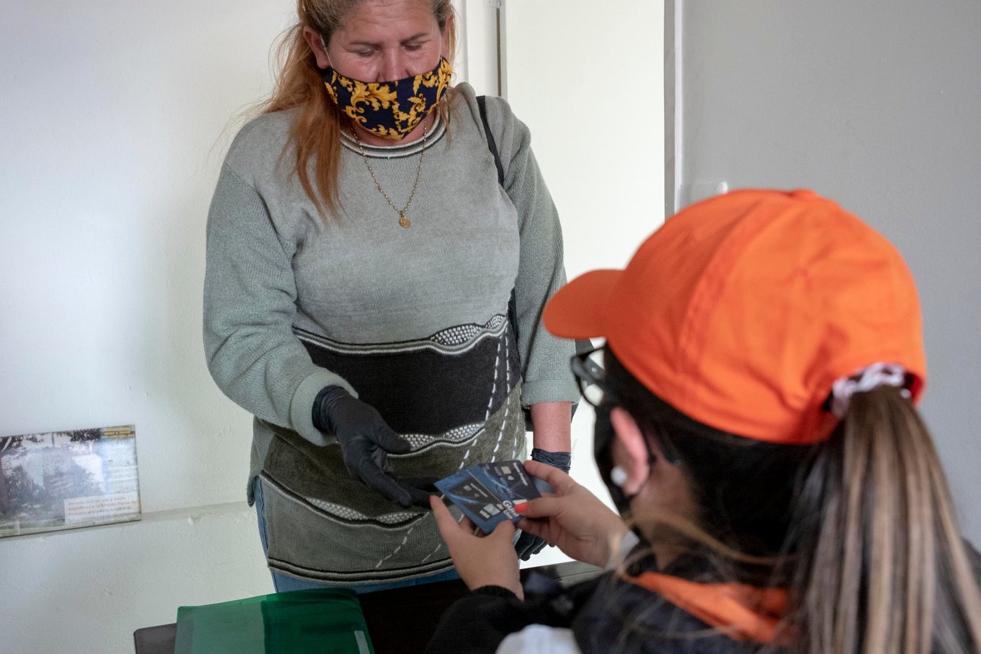 June 25, 2020. Bogota, Colombia: Lisbeth Chiquinquira (53) is receiving the cash aid in the form of a card given to her by a worker from the NRC team after checking her documents. She is originally from Maracaibo. She has 7 children, of which only one is still in Venezuela. There, she has a little house. But in the five years she's been gone, the house has been abandoned. At first, she lived in Becceril, near the Colombian Caribbean coast with her sons and daughters. They were paid to keep a house; but when it was sold, Lisbeth came to Bogotá, a year and 7 months ago, with a daughter and two of her grandchildren, aged 12 and 9. "Here I am working selling coffee on the street. Thank God, I did very well last year but with this cvid-19 issue, I haven't been able to work. I go out with my thermos, but the covid with the coffees... it doesn't happen! People don't buy out of fear. Before in Venezuela, I worked in a family home, I was an employee." (...) “This year, yes, it has made me quite difficult. I don't have to give up my son who is in Venezuela, who has two children. Yesterday he called me and said: Mommy, I want to leave. But no! The situation is very difficult. Just to bring him to Maicao [on the Colombian side, near the northern border with Venezuela], they are charging 100 dollars. And from Maicao to Bogota... other money... And since they're not letting anyone through, I have him there, in great need." When asked what her hopes are, Lisbeth replies: "That my country will return to what it was and we will return! Yes, I am very grateful to many Colombians, but yes, I would like to return to my country. There is my family. There is my little house. I have a sister, I have nephews and nieces. I have faith in God that one day it has to happen. Each one of us must return to our own homes, to our own country. To live our life, as we lived it peacefully. Happy. We were very happy." Credit: Nadège Mazars for NRC