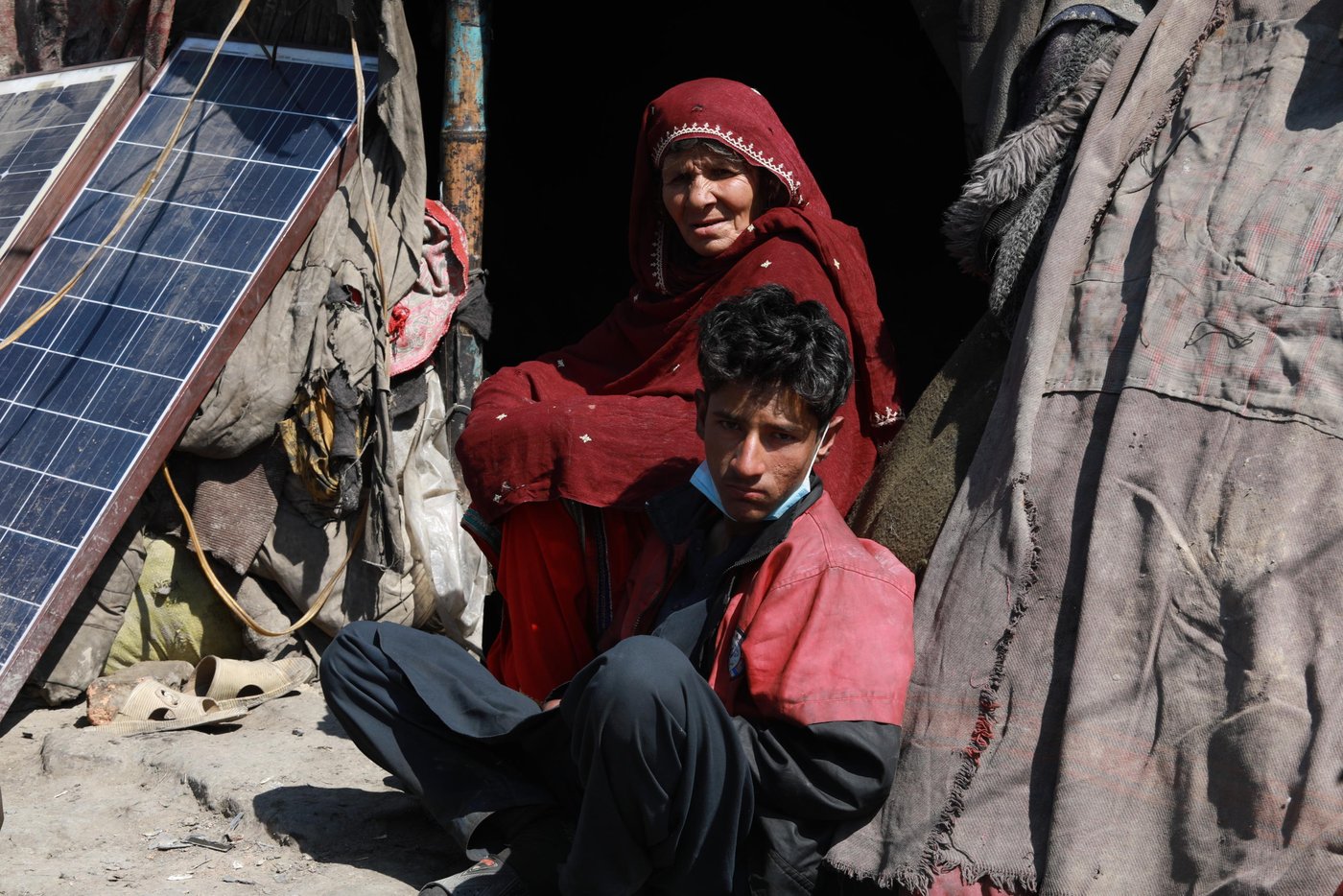 Shayista Gul, 60, and her son Esmatullah, 17, sitting in front of their makeshift shelter on the outskirts of Kabul city. The family have been living in this IDP settlement for 13 years now since the time they have been returned from Pakistan where they lived as a refugee. The family has no source of income since Esmat lost his father in an explosion in east Nangarhar province who was the primary income generator of the family. Now, 15 people, including Shayista’s daughter and her children, who also lost her husband in the same explosion are living in a two-room makeshift home.

Quotes from Shayista: “Since the outbreak of this diseases the price of food items are raised to double folded. I went to a nearby shop this morning to buy soap and detergents, but I could not buy it as the price was increased. Now, I’m washing my clothes only with water without using any detergents.” “we are staying on government owned land and there is no borewell or water tap close to the settlement. It takes at least five minutes to fetch water from a well inside another colony.” 

“We usually rely on community donation here and I heard that price of a bag of flour had increased by 1200 (approx. $16) yesterday and in this case, families might not have sufficient food themselves to help us anymore. We noticed that everyone who could afford was rationing foods and we are just left like that. If things get worse in the coming days or weeks and food and vegetables falls short and shops remain close, we will be left hungry and might lose our loved ones.” “even if the government ask us to stay at our homes, we can’t. we have to collect scrap to feed our children. If not, we die out of hunger and not having food. If Coronavirus do not kill us, hunger will, definitely.”  
Photo: Enayatullah Azad / NRC