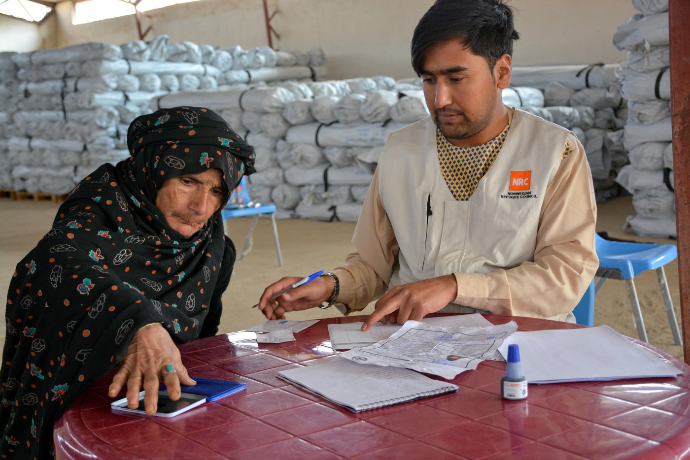 Gul Ghotay puts her finger prints at the bottom of paper to receive a tent from NRC in Qala-i-naw.
Gul Ghotay, a widow lives with her two daughters and a son in Feristan IDP settlement. Her husband died five year ago. Her oldest son is separated and living in Herat with his family. Her second son has become an opium addicts and she doesn’t know about his fate anymore. Zalmay, 17, her youngest son and her lost hope has been affected with Tuberculosis TB in the settlement. The family was living in substandard makeshift home in the river bed of Feristan settlement.
Though Zalmay is suffering from Tuberculosis, but he is the only breadwinner for his family of four. He has recently started selling sandwich in the market.
“we weren’t bothered by heat neither were we cold in our village. We are suffering all the time since we have been displaced. My son was healthy and now he coughs for hours or sometimes he brings out all his clothes and the other time he feels cold and asking me to put all the blankets over him. He acts weirdly and sometimes he doesn’t want to eat for days. The doctors say he has to eat plenty of fruits, vegetables and chicken meat, but the problem is that where can I get those all for him?”
“The doctors in Badghis told us to take him to Herat. We didn’t have enough to take him there. So I borrowed 10,000 AFN (Approx. $140) from my brother and took him there. The doctors give him some medicine and asked to visit them frequently. Now I don’t have enough to take him in Herat or buy him medicine."
Zalmay, 17, is infected with tuberculosis in Feristan IDP settlement where he and his family lived for over five months.
“I felt pain in the chest at the beginning and then was coughing. I didn’t tell my mom unless it got worst. I went to doctor and the doctors said I have been infected with tuberculosis. They gave me medicine for two months and asked me to visit them again. There have not been any changes or progress in my health. I still feel pain in my chest and coughing up blood.”
Photo: NRC/Enayatullah Azad