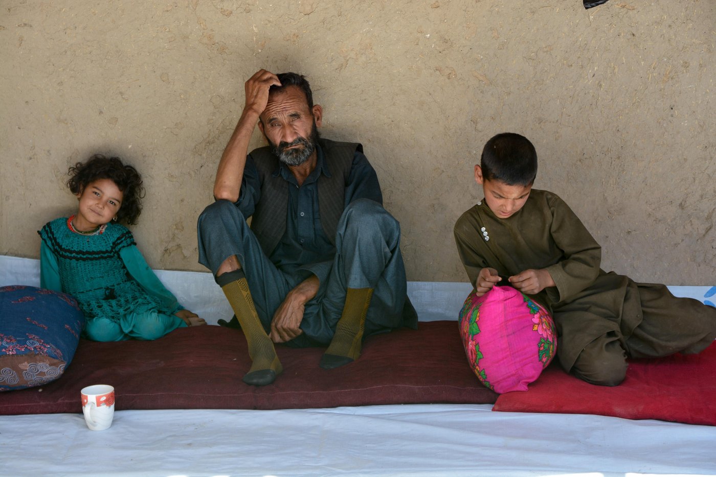 Ghulam Yahya, 72, among his grandchildren Hania, 6, on left and Ayatullah, 9, on the right hand in Chilangum, inside provincial capital of Sar-e-Pul city.
He was held captive and tortured by Taliban militants, but he was so lucky they didn’t kill him.
Malek yahya was among the village men that Taliban had separated them from women. They didn’t kill him, but tortured and interrogate him. “They didn’t kill me because I was Malek and had good relation with my neighbors and the Taliban knew me or because I was suffering from diabetes and my eyes have lost sight,” he said.
“They tortured me and were questioning me about the village men and weapon. They searched every houses and looted them. They took all animals and distributed the house assets among them.”
Malek yahya was among 235 including women and children abducted by Taliban militants on August 4, and was released on 8 August 2017, but over 70 were summarily executed.
Photo: NRC/Enayatullah Azad