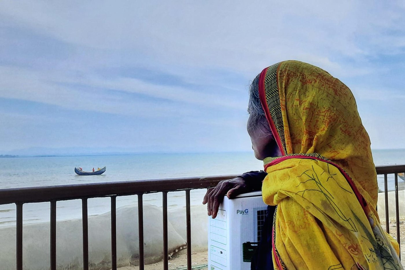 Isamon bibi sitting beside the shore with her solar panel box. She says, “I can sleep better tonight”. Photo: Ayesha Nawshin/ NRC