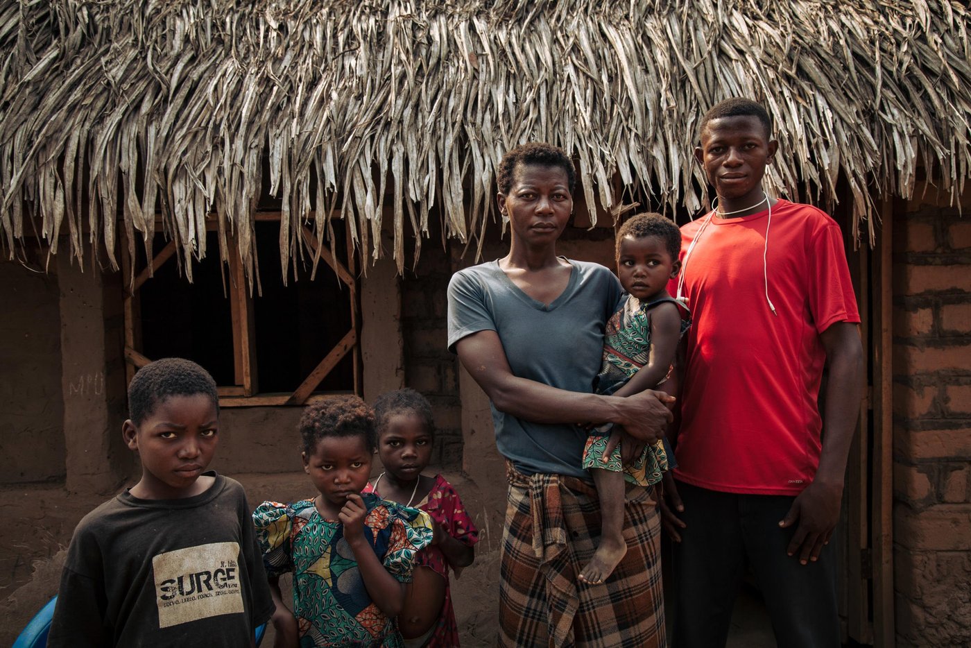 Sangamai Teka, a 41-year-old farmer and mother of 9 children (two children died while they were in exile in the forest), poses with five of her children in front of her new NRC-funded home in Mbulungu village. 

Since the attack, by armed groups, on the village in March of 2017, she has been alone and does not know the whereabouts of her husband. 

"When the war came, we ran for refuge in the forest," she explained. "There we had nothing to eat and we all got sick. Of the nine children I had, two died. I had to bury them in the forest." 

Sangamai is one of the beneficiaries of the cash-for-shelter program launched by NRC in 2017. 

Over 1 million people have returned to their homes in Kasai-Central after a year of violent conflict within the province and across the Greater Kasai Region.  Unfortunately, people who have returned have found their homes and fields pillaged and burned to the ground.  These farming communities have no shelter, no food to eat and no means of sustaining any viable livelihood.

Earlier this year, NRC visited Mbulungu and Bakuakashila, two villages ravaged by the regional conflict in 2017.  NRC used its “community-based approach” by consulting with these communities to better understand their primary needs, to properly target the most vulnerable people and facilitate their ability to choose the assistance they require.

This intervention, however, is only a drop in the ocean of the vast needs of this community.  NRC is currently the only humanitarian actor in the zone and funding is not enough to address other acute needs such as food assistance, household items and education.  The Humanitarian Response Plan is currently only 25 per cent funded eight months into the year.  Humanitarian capacity is critically low.  If donors do not act now for the people of Mbulungu and for the rest of DR Congo, it will be too late.

August 29, 2018- Kasai-Central Province, DR Congo
Photo : NRC/Aléxis Huguet