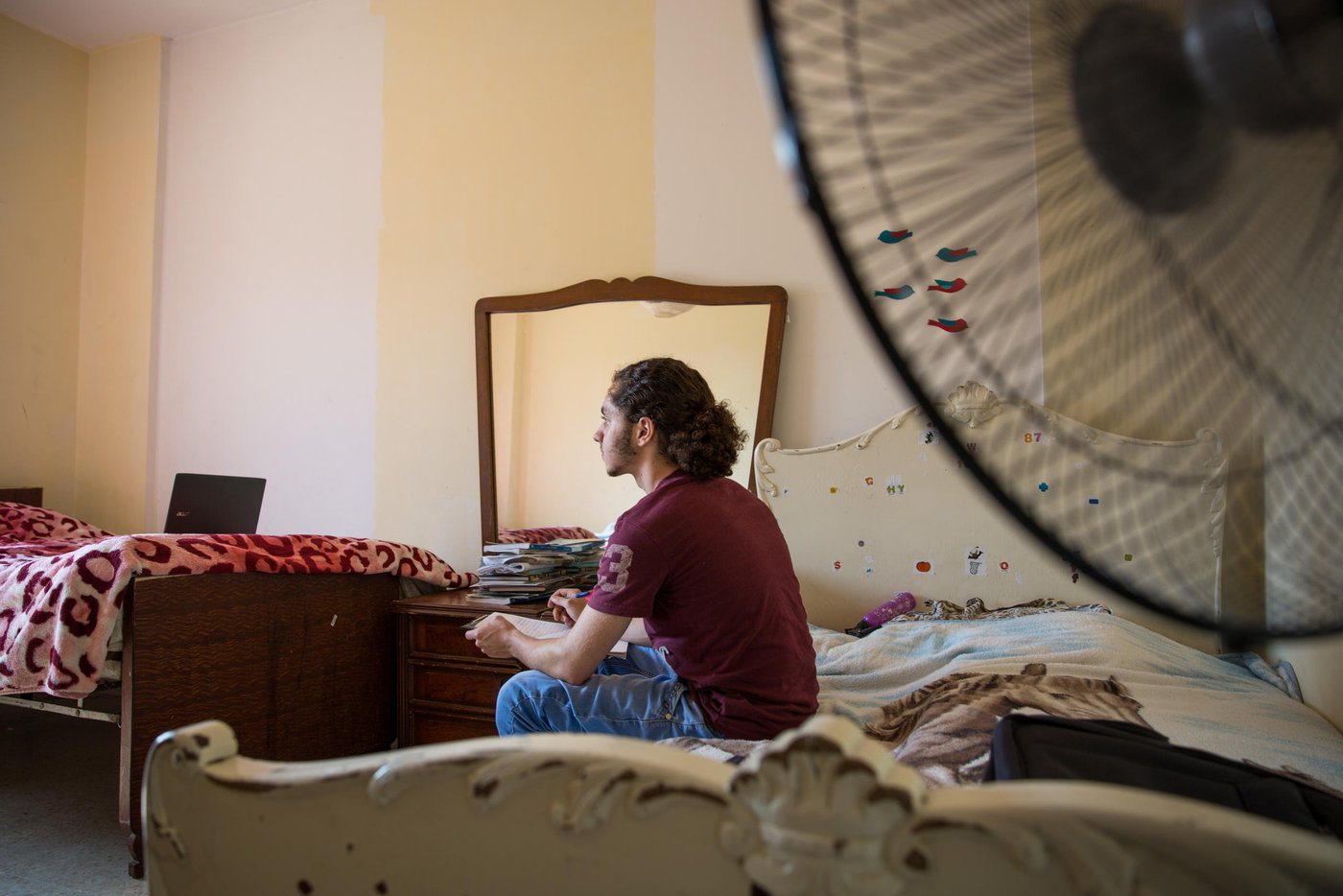 When Osama was 15 years old he fled from the war in Syria together with his parents and four siblings. Now, five years later, he is 20 years old and has just seen his dreams for the future shattered yet another time.
Osama grew up in the outskirts of the Syrian capital, Damascus. A modern, vibrant and stable city until the war broke out in 2011. He lived a normal life. Went to school. “My country was a nice place to live in. I reached grade 10 in this school. I loved being there,” says Osama. “We lived in an area like Beirut. There were buildings and streets, it was not a village. Our flat was on the ground floor, with three rooms and two gardens. It's awful, because when I was a child, I had a dream to build my future life in that area. I wanted to become a doctor, and open a clinic in my house. My father and mother used to tell us, my siblings and I, that we will transform the house into a medical centre, each room for each one of you. But we cannot do it now. So, I should find alternative solutions, alternative dreams.”
“Maybe you heard about the chemical attacks in 2013? We were near the spot where the chemical attacks happened. After the attacks, president Obama said that he will attack Syria or some points in Syria, so we left. We decided to leave Syria for 3 months, we hoped that the condition in our country would become safer. But the conditions stayed the same, not stable.”
“Maybe I should start with the positive things. I am a student in the university. I got a scholarship here. My family is with me. I am sure this is a good thing. My friends' families stayed in Syria.” The dream of becoming a doctor and open a clinic is put on hold for Osama. “Now, I am a computer science student, maybe I will find myself there. I hope I can open a mobile school to teach people.” To be closer to university, Osama lives in a shared flat with nine other Syrian youths in central Beirut. They are close knit group who support each other through thick and thin. His family rents an apartment outside Beirut, and Osama spends his weekends there with them.
For a Syrian refugee living in Lebanon, there are many limitations. Osama and his older sister are the breadwinners of the family and feel the big burden on their young shoulders. “Even if you found an opportunity to complete your education, and you have a master degree or a PHD for example to become a doctor, you are not allowed to work. Living here is very expensive, so you need a lot of money. My biggest challenge is that the economic situation is so bad, not for me, but for all the Syrian families.”, says Osama.
“Maybe the bad things here, as a Syrian guy in Lebanon, there are a lot of regulations that restrict my life, which make me not like a normal guy. Right now, I don’t have an official residency, so I cannot go to every place I want. I entered Lebanon legally, but you have to pay $200 per year for each person above 15 years old for a residency permit. So, if your family consists of seven members like ours, you have to pay $1000 yearly. I didn't pay, so they took my passport and now I cannot move or leave this country.”
Osama and his family have tried to find another way to build their future elsewhere. They applied for resettlement. After a long process, including two interviews, Osama got the phone call. They were rejected. “I feel I am in a big jail. Like an animal in a zoo,” says Osama with tears in his eyes. The rejection was a big blow for Osama and his dreams for the future for himself and his family. “I cannot go back to Syria, and I cannot leave this country. So, I will try to live here.” Osama tries to think positive. “I consider Lebanon my second country, I love Lebanon so I want to serve this country. I want to build my family here. When I came here they said welcome, so I owe them one.”
Photo: Ingebjørg Kårstad/NRC.