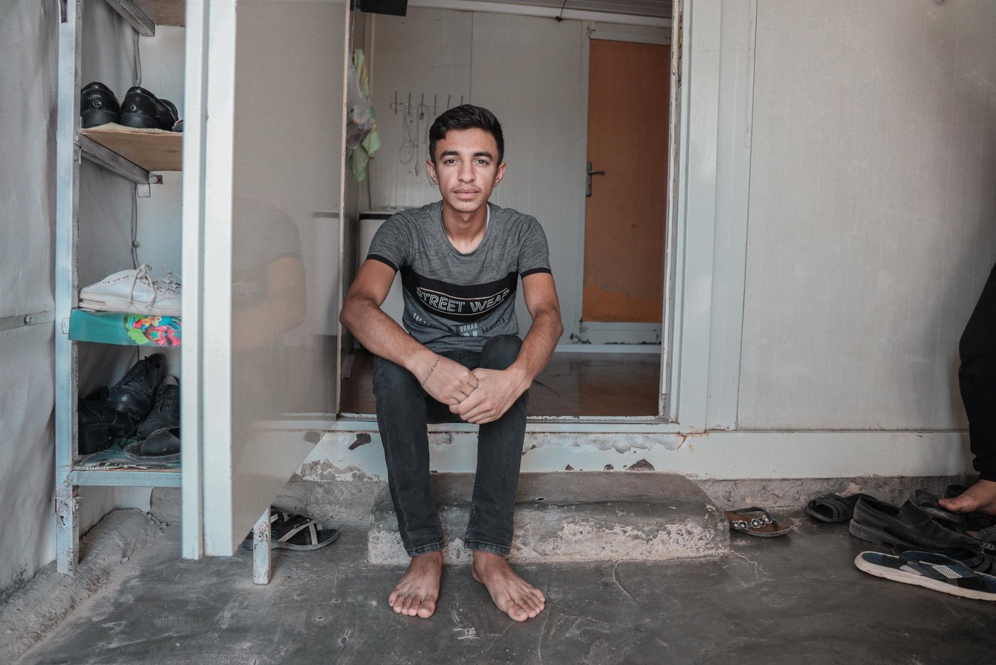 Photo: Alan Ayoubi /NRC

Description: 15-year-old Salam. It has been four and a half years since Salam arrived at the Qadiya (Rawanga) camp in Duhok, Iraq. His family had to flee Sinjar when the Islamic State group captured the city. 

Interview: 

My name is Salam, I am 15 years old from Sinjar. We’ve been living in this IDP camp for the past four and a half years.

[Note: The Qadiya Rawanga Camp in Dohuk hosts 2,640 families and a total of 14,284 individuals] 

Do you go to school?

I just passed the second stage of secondary school [ he graduated grade 7], but this year we only went to school for the first semester of the year. We did not go to school for the second semester and we did not take the final exams, they used our first semester marks for the second one as well.

What has COVID-19 changed in your life?

It has changed many things for us and the first thing is school. We did not finish our books properly. We also used to attend summer school every year as preparation for the year ahead, but this year because of coronavirus, there is no summer school. 
In my daily life, we can not go out like before and even if you go, everyone talks about the coronavirus. Same thing on the internet, that’s all everyone is talking about.

What do you know about COVID? How has it affected you and your family?

I don't know details about the virus but I know it can kill people, and also that it affects people economically. It has definitely affected my family financially. My father is working in construction, but now he is no longer going to work like before. He used to work every day, now he works one day a week or less. We can’t afford to buy clothes, or new books anymore because of the situation. 

As the oldest child, are you worried that you might have to look for work yourself to support your family?

I've already thought about that [to start working], but the problem is there are no work opportunities out there, not only for me but also for my father. Some of my friends were forced to work to provide daily necessities, but the work was only for few days during potato harvest season. Even if I had to work or wanted to work, there are no jobs.


What are you most scared about COVID and why? 

I worry that we cant go back to school next year. We would need to do everything online which is hard. Right now I watch tutorials on Youtube to learn the English language. 

How do spend your days?

I play PUBG game [a mobile game], I study the English language. I read or do school work about 4 to 5 hours a day but the slow internet service has been a challenge.
 
How has coronavirus affected you or your siblings? since you are not going to school and you are all in this small caravan 24/ 7.
When I get stressed I just stay silent and numb.
It’s hard because all of us are at home all the time. I have 2 sisters and 2 brothers. Often we argue and get mad at each other.

SIBLINGS:
Hanan, 15, studies in stage 2 in secondary school
Lina, 13, studies in stage 5 primary school
Luaya, 8, is in the second stage of primary 
Dilshad, 6, in the first stage of primary school

What do you do to overcome stress?
I talk to my friend through the internet, we play games, I read my school materials, and sometimes I watch TV.

Your hopes for the future? 
I want this virus to vanish soon so we can go back to school. 

What about your siblings, what do they do? 
They usually play right outside and around our caravan.

Their Mother (Fatee) talks about the effect of coronavirus on her children ...
Their behaviour has changed a lot, there is a lot of tension between them as they are usually at home, they no longer see their friends like before. Also, we can not spend on them like before, because of coronavirus their father can't go to work every day.