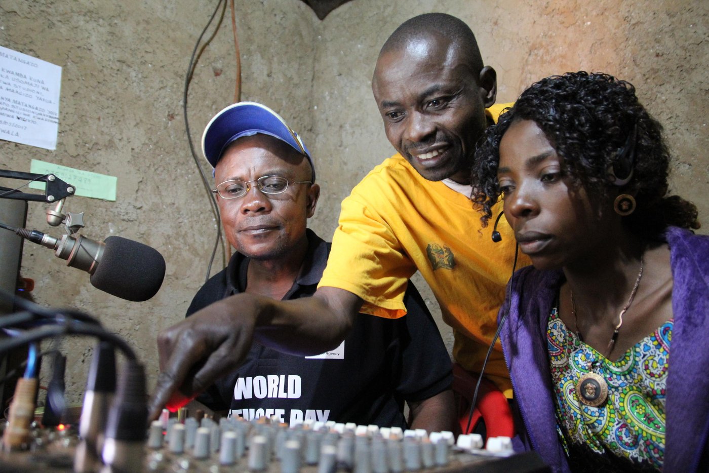 Radio Umoja was established by Jonathan (in yellow t-shirt) in March 1997. When he first entered Nyarugusu refugee camp, he observed that there was a lot of misinformation or lack of information reaching refugees on issues affecting them. He immediately swung into actions. Using available resources, he acquired a loud speaker and a small transmitter and during the evening he would announce information that he had acquired through UNHCR and other agencies through the loudspeaker. Many people used to come to gather around the loudspeaker to listen to latest information.
Gaining acceptance and support, he started putting together radio station equipment through support from humanitarian agencies. He also obtained a 6-month license from the Tanzanian government to broadcast information. During the six-month pilot phase, he received supervision and content scrutiny from Tanzania’s Ministry of Home Affairs.
He used to get permits to stay out of the camp in order to travel to Dar-es-Salaam capital to follow up on equipment such as transmitters, microphones and studio controls. He also received permits to bring on board radio announcers and field reporters.
His main goal is to use the radio station to raise awareness among the refugee population about pertinent issues and solutions. For example, how the youth can be productive and avoid engaging in criminal activities. He also speaks out against sexual violence targeting women and girls. The radio transmitter covers a radius of 30 kilometres. “People in Nyakitonto usually call the studio to say that they can hear our voices loud and clear,” says Jonathan.
Initially his radio station was called ‘Radio Taarifa Tangazo na Salaam’ (RTTS), translated as News, Announcement and Greetings Radio. Later he decided to specialize in religious songs and changed the name to Umoja Radio, which means Unity radio. There are 26 workers in the studio, including security staff, editors, cleaners, field reporters among others. These are all volunteers.
Operational challenges
“Lack of funds to pay workers and services that we receive is the biggest challenge. This leads to a high turn-over since the workers also need an income to support their families,” says Jonathan. This means that the radio station cannot operate optimally since fuel shortage are bound to occur. 15 litres of petrol is needed per day to guarantee full-time broadcast, while a litre of petrol costs 2,500 Tanzanian Shillings (XXX US Dollars). Jonathan has a better idea, he thinks that solar as an alternative green power option can solve all the energy and fuel demands.
As can be expected from a remote refugee camp like Nyarugusu, there are other challenges faced by the radio station staff. “The station infrastructure needs an upgrade. We need to fix the ceiling, buy office facilities such as tables, chairs, shelves, monitors and central processing units. We are also using an improvised antennae to transmit radio frequencies,” says Jonathan. Most importantly, they need money to pay for transport for field reporters, or to purchase a scooter for ease of transportation.
Umoja Radio broadcasts from 6am up to midnight on Sundays to Thursday and 24 hours on Fridays and Saturdays. However, due to shortage of fuel, radio hours can sometimes be shortened. To subsidize running costs, they sometimes sell greeting cards and on-air advertisements. “Listeners are not happy when we shorten the radio hours,” says Jonathan.
The most popular programmes are “Vijana na Maendeleo” (youth and development), “Sauti ya walemavu” (voices of people with disabilities), “Wakati wa utamaduni” (Time for traditions) and “Afya yetu” (Our health). Except for one, all other programmes are broadcast in Swahili language which is well understood by both refugees and host communities. They also publish a monthly magazine called “Mwangaza” which means “Rays of light”.
Community engagement
According to Jonathan, it is very important to work closely with the refugee community and be seen to be part of camp activities. We cannot afford to operate in isolation, any perception of being an ivory tower automatically leads to loss of trust. For example, a children’s parliament visits the radio station once every term to discuss and debate issues. Listeners can also call in and express their views.
The station is running broadcast courses for students who are interested in journalism. The third cycle of courses has been started with a total of 21 students. Twenty-one learners completed the first cycle, followed by 17 students on the second cycle. They hope to secure their own building structures to offer the courses. Subjects taught include History of radio and broadcasting, language of radio, communication processes, broadcasting chain, interview techniques, radio production, advocacy and media ethics.
Radio staff regularly visit local hospitals to speak with patients and discuss health issues. These inform health programmes such as ‘Ugua pole’ translated as ‘quick recovery’. However, at times the hospital staff and management become hostile towards field reporters and put a ban on speaking to the media. They also visit farmers to better understand their livelihood activities and farming methods.
“Generally the host communities perceive refugees as troubled people who have fled their country and cannot depend on themselves for daily survival. We are also perceived as people whose movements are restricted, which is a challenge when we try to access services. When I used to travel to Dar-es-Salaam using my movement authorization people used to be suspicious when I informed them that I was a refugee. One man suspected that I was plotting a coup to overthrow the government,” he says. In addition, host communities perceive refugees as being criminals or lazy. He hopes that through his programmes, he can help to reverse the negative attitudes.
Online radio
Interestingly, Umoja Radio can also be heard through the internet and through mobile App ‘Umojaradio’ which can be downloaded via Googla Play. To listen to the radio via the web, go to: www.umojaradio.nl. On Facebook, the address is ‘Umoja Radio Nyarugusu’. Through the internet, they are able to reach millions of active and potential listeners. Listeners regularly send greetings from as far as the United States of America, Australia, The Netherlands and South Africa. One listener from Norway also showed up at one time. The main challenge is that they rely on a modem with a speed of just 7.2 Megabytes per second.
Background and early days
Jonathan has spent 20 years in Nyarugusu camp. He first arrived in 1996 fleeing tribal conflict locally labelled ‘Songa Mbele’, or ‘move on’. He was born in Fizi Zone in the Democratic Republic of Congo. He is 47 years old. He started learning about radio in the DRC. He used to write articles for ‘Jua’ newspaper (Jua means Knowledge in Swahili language. He was a reporter for Radio Channel Africa from 2004 to 2005.
Quotes from Jonathan:
"I am working here at Radio Umoja situated in the Nyarugusu refugee camp, I am happy because our radio station informs and teaches the refugees all the time. We begin our broadcast at 8am in the morning until midnight."
"It is important that refugees listen to the information through our radio. It is important because they listen to information across the world from Nyarugusu."
"Radio Umoja is independent and belongs to the refugees. This includes the refugees from Congo DR and Burundi as well."
Photo: NRC Ingrid Prestetun