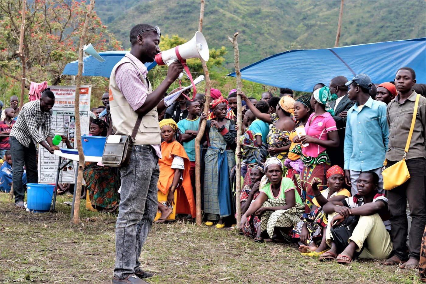 Remy Mutu is a local consultant who has worked with the Norwegian Refugee Council in DR Congo to provide aid assistance to people from his community. Remy stands in front of a crowd of displaced people who came to get assistance at the market that NRC has organized in Mulima village.
With support from the European Union Civil Protection and Humanitarian Aid (ECHO), NRC has provided aid assistance to 13,000 displaced people who have received e-vouchers to buy households items like mattresses, blankets, pans, clothes, plastic sheets, etc.
November 2019
Photo: Ephrem Chiruza/NRC