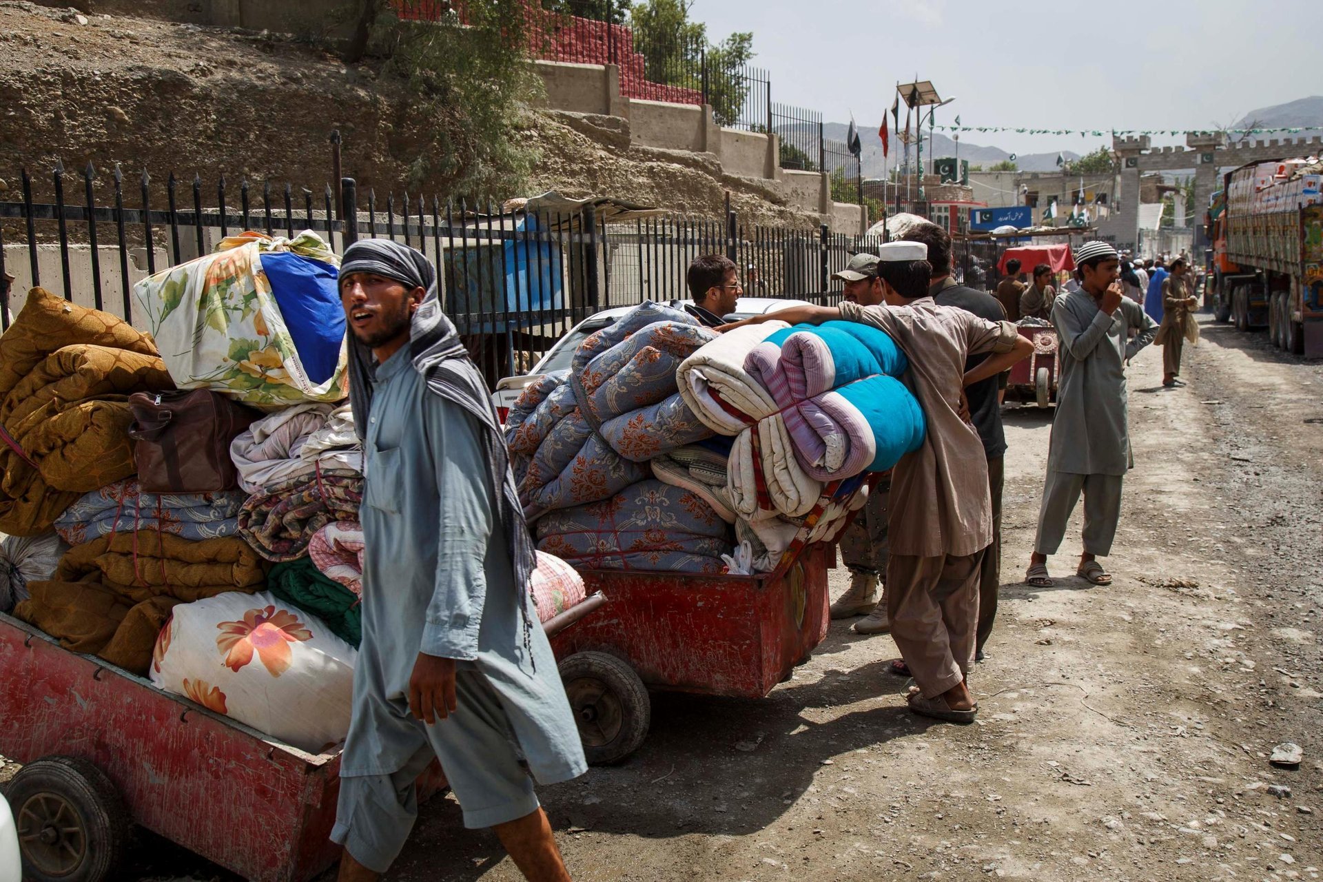 Some undocumented returnee families are too poor to afford lorry rental to transport their goods, and can only move what they can carry on public transport and by foot. This family brings blankets and clothes through the Pakistan border by wheelbarrows. Border staff estimate 40-60 returnee families cross without vehicles every day. (Photo: NRC/Jim Huylebroek)