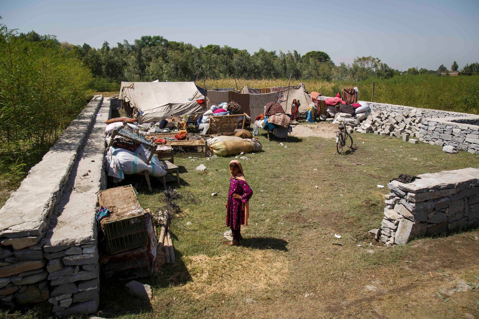 A girl stands in front of her family’s tents—her new home after her father and uncle felt forced to leave Pakistan four days ago. There is no water or bathroom here, and they only have food enough for a few days. (Photo: NRC/Jim Huylebroek)