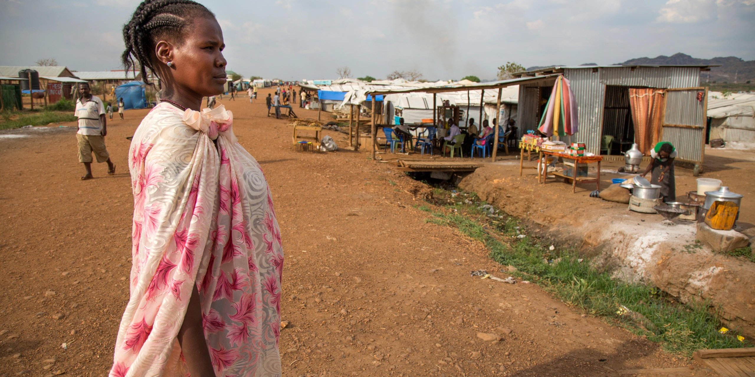 30 November 2016. Juba: Nyakuan Dador, originally from Mangatein, walks at the UN Protection of Civilians (PoC) site in Juba, South Sudan.
Nyakuan, mother of six children, doesn't know the whereabouts of her husband who is a member of the opposition forces. She has been displaced with her children since the civil war started nearly 3 years ago. The conflict officially broke out on December 15, 2013, between forces loyal to President Salva Kiir and those loyal to former Vice President Riek Machar. Since then, an estimated 1.6 million people has been displaced inside the new country's borders. In addition, more than 640,000 people have fled to neighbouring countries. Hunger is on the rise.
According to OCHA, more than 6.1 million South Sudanese are in need of protection and humanitarian assistance such as food, clean water, education and other basic services.
Nyakuan Dador's story:
Nyakuan moved to the PoC right after the conflict started in December 2013. Her husband goes regularly in and out of the IDP camp to work as a trader in different villages to help the family to move on. “But it’s really hard to sustain our big family with so little income,” she explains. That’s why she also runs a small restaurant at the PoC.
Nyakuan complains about the lack of good education and healthcare, and even food. “Life was very different before the war,” the woman remembers, “in our homeland we used to have money to pay the hospital and school fees.” The mother regrets they are totally under the assistance of the humanitarian organizations. “These organizations are our parents now,” she says.
Nyakuan is a real supporter of good education in the PoC. “If our children go to the school everyday, they will become something good in the future,” she believes. However, Nyakuan admits that teachers are not paid and school materials are very short. That’s why her only message to the international community is providing support on education for the new generations.
“It has been a long time since we celebrated a proper Christmas,” Nyakuan says. She would like to cook something special for her guests, “but now there is nothing to prepare and no guests to come to my shelter.”
----------------
Photo by Albert Gonzalez Farran - NRC