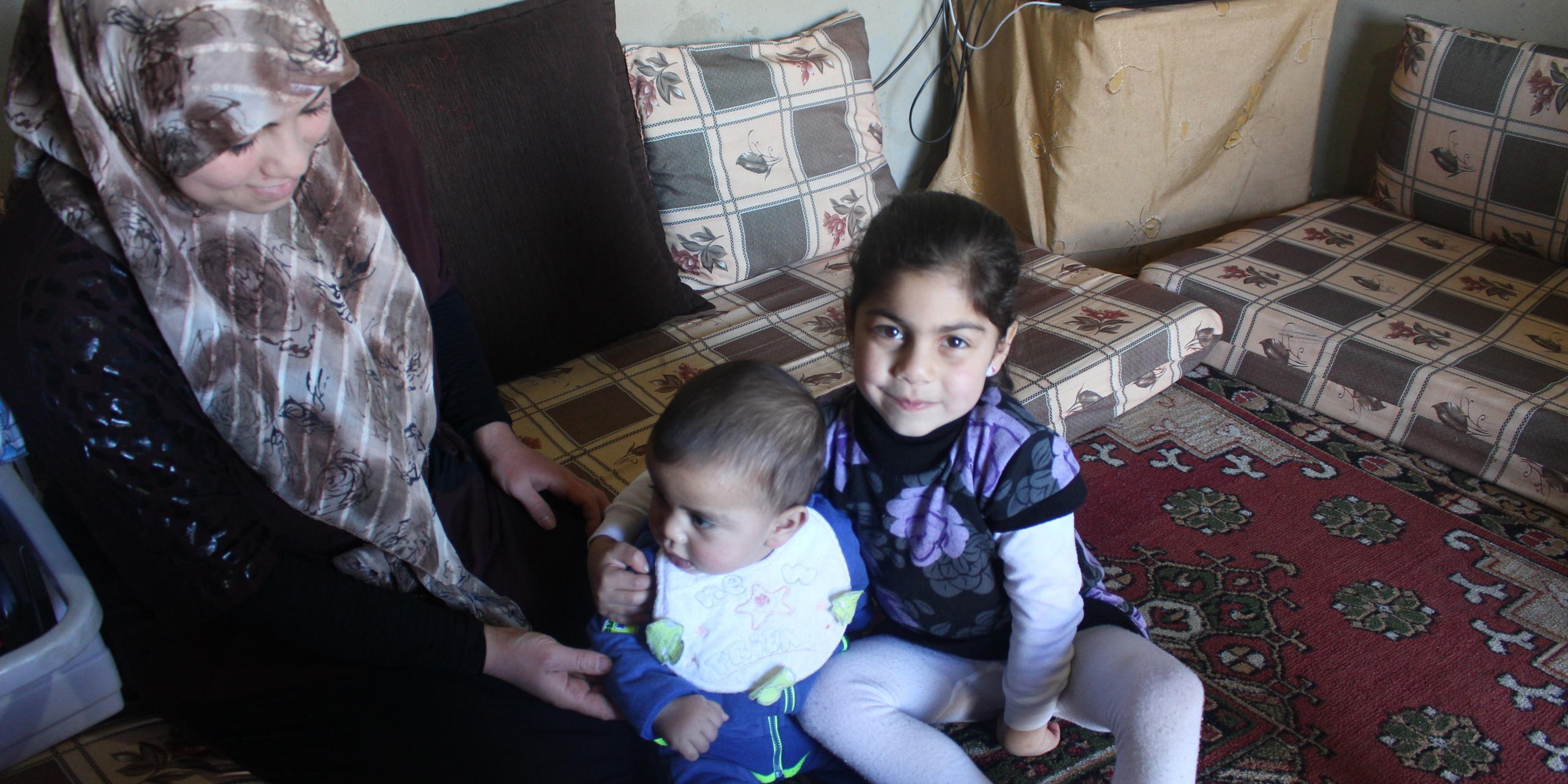 Ilham, her younger brother Youssef, 9 months old, and their mother Safa, 26, in the family's living room in South Lebanon. Youssef was born in Lebanon and his parents have not yet registered his birth, which makes him at risk of being stateless. NRC’s Information, Counselling, and Legal Assistance (ICLA) team are supporting Youssef’s parents to formally record Youssef’s birth.

Photo: NRC/Rayane Abou Jaoude