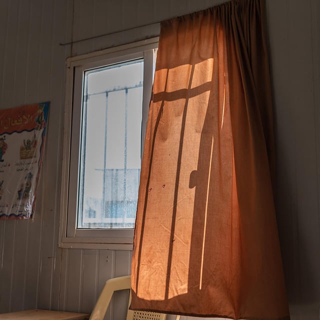 A curtain gently blowing in the wind from an open window.