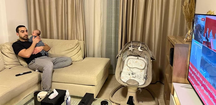 En pappa och hans bebis tittar på nyheterna hemma.