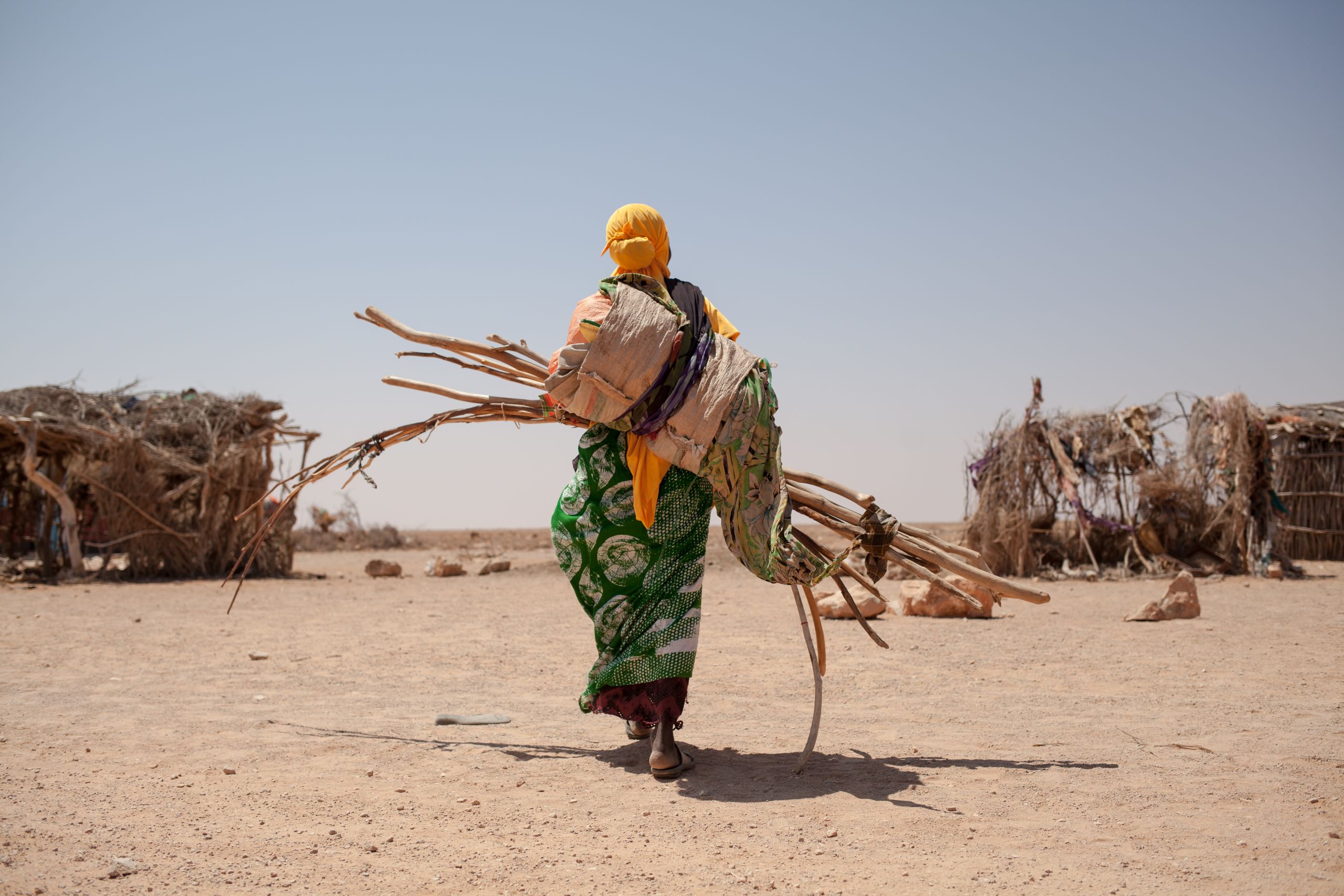 60 familier har flyktet landsbyen Shisha i Somalia og dermed doblet innbyggertallet. Miglo Barre bærer materialer for å bygge husly til seg og sine fem barn. Foto: Adrienne Surprenant/Flyktninghjelpen