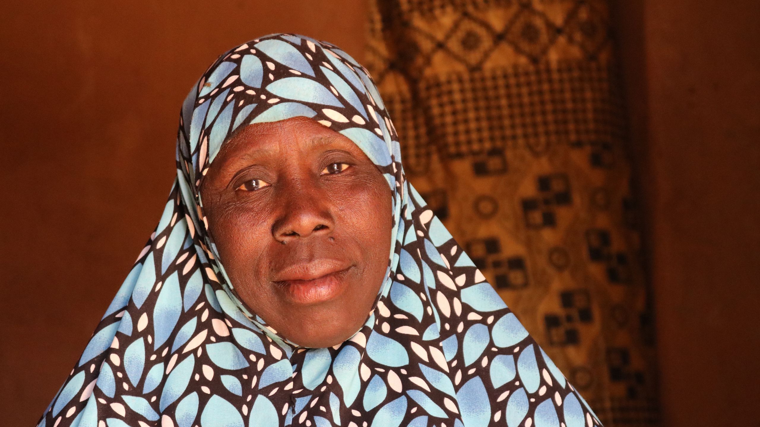 Portrett av en kvinne. Hun har et blåmønstret sjal på hodet.