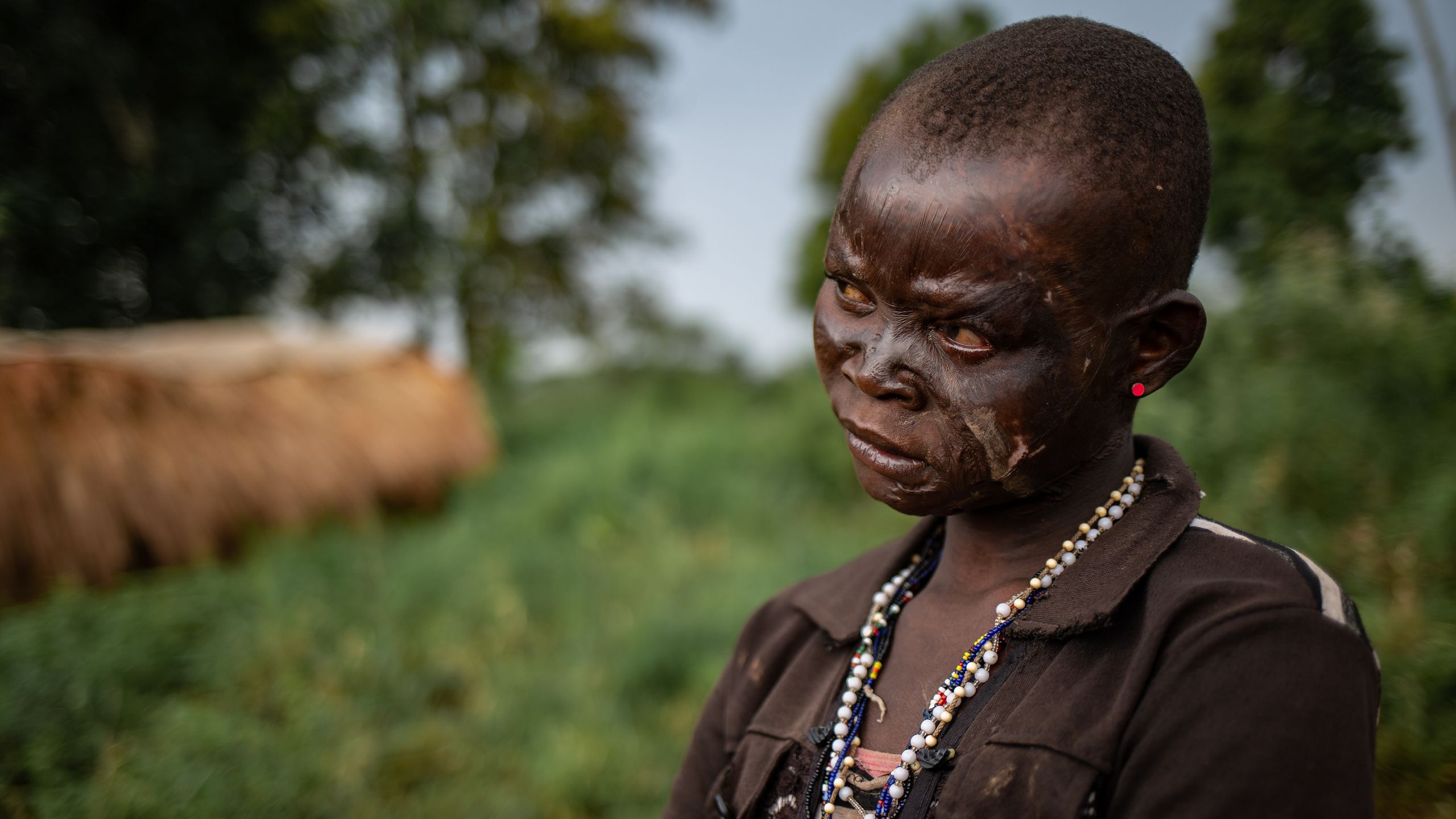 Portrett av en kvinne. Hun har et perlesmykke rundt halsen og en rød øredobb i øret.