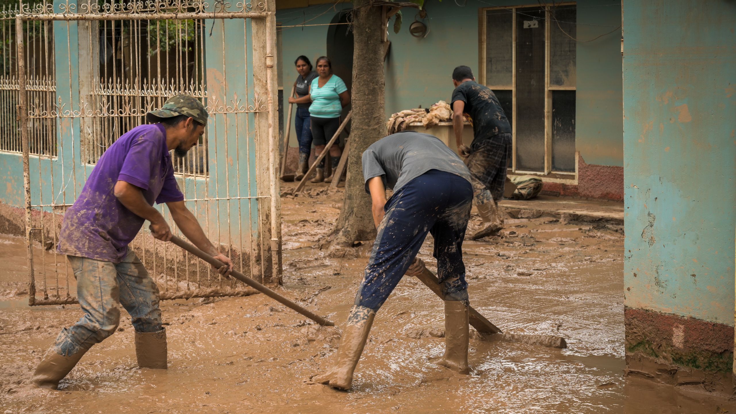 To personer jobber med å fjerne gjørme fra gatene etter en storm.