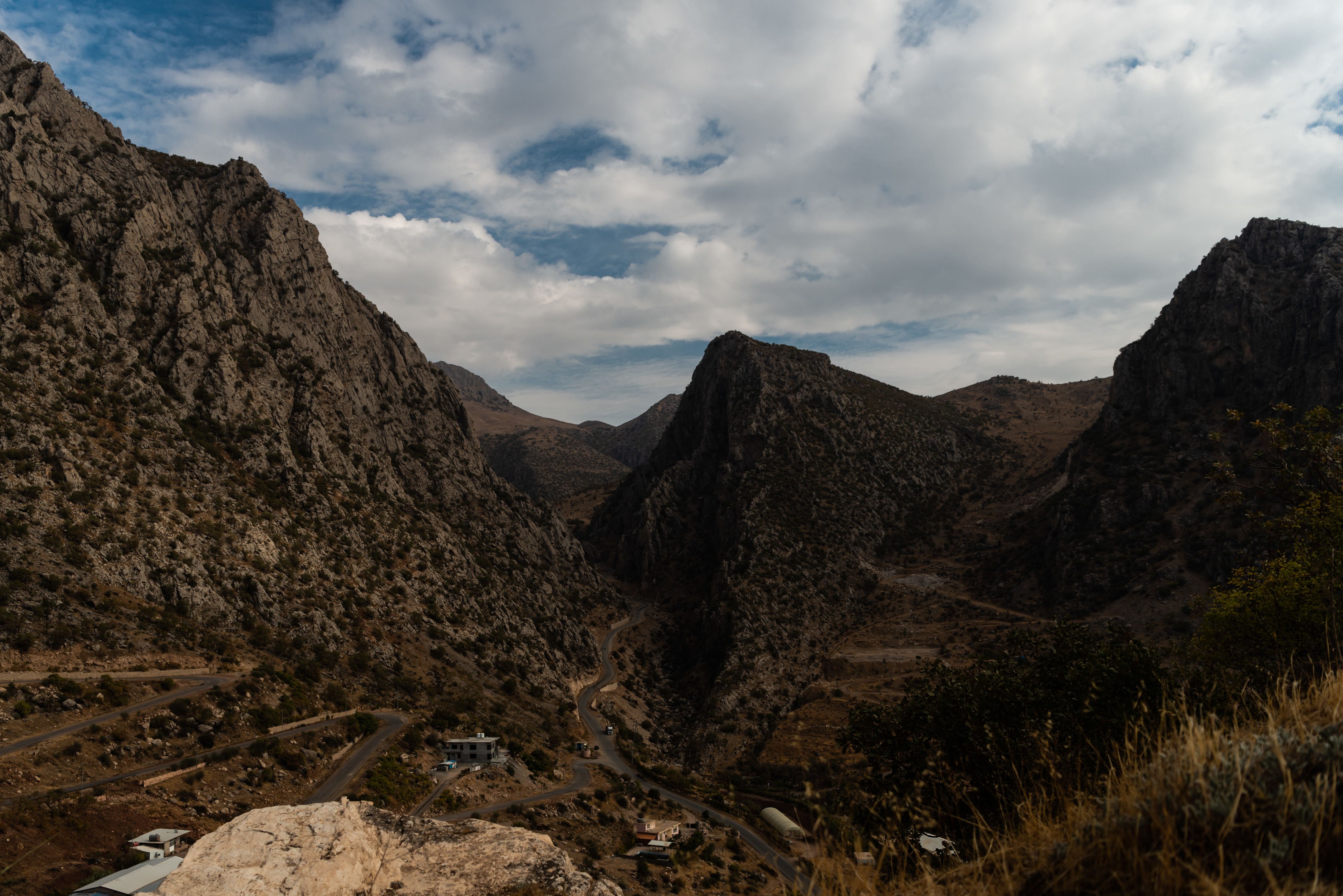 En fjellvei snor seg gjennom høye fjell i et tørt landskap.