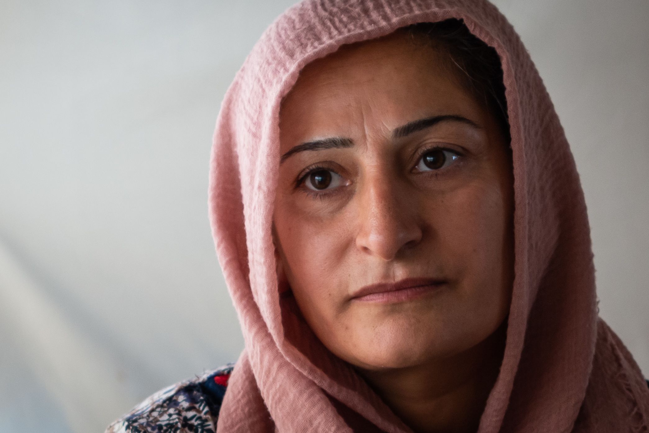 Nært portrett av Kamla. Hun har et lyserosa sjal rundt hodet. Blikket er alvorspreget.