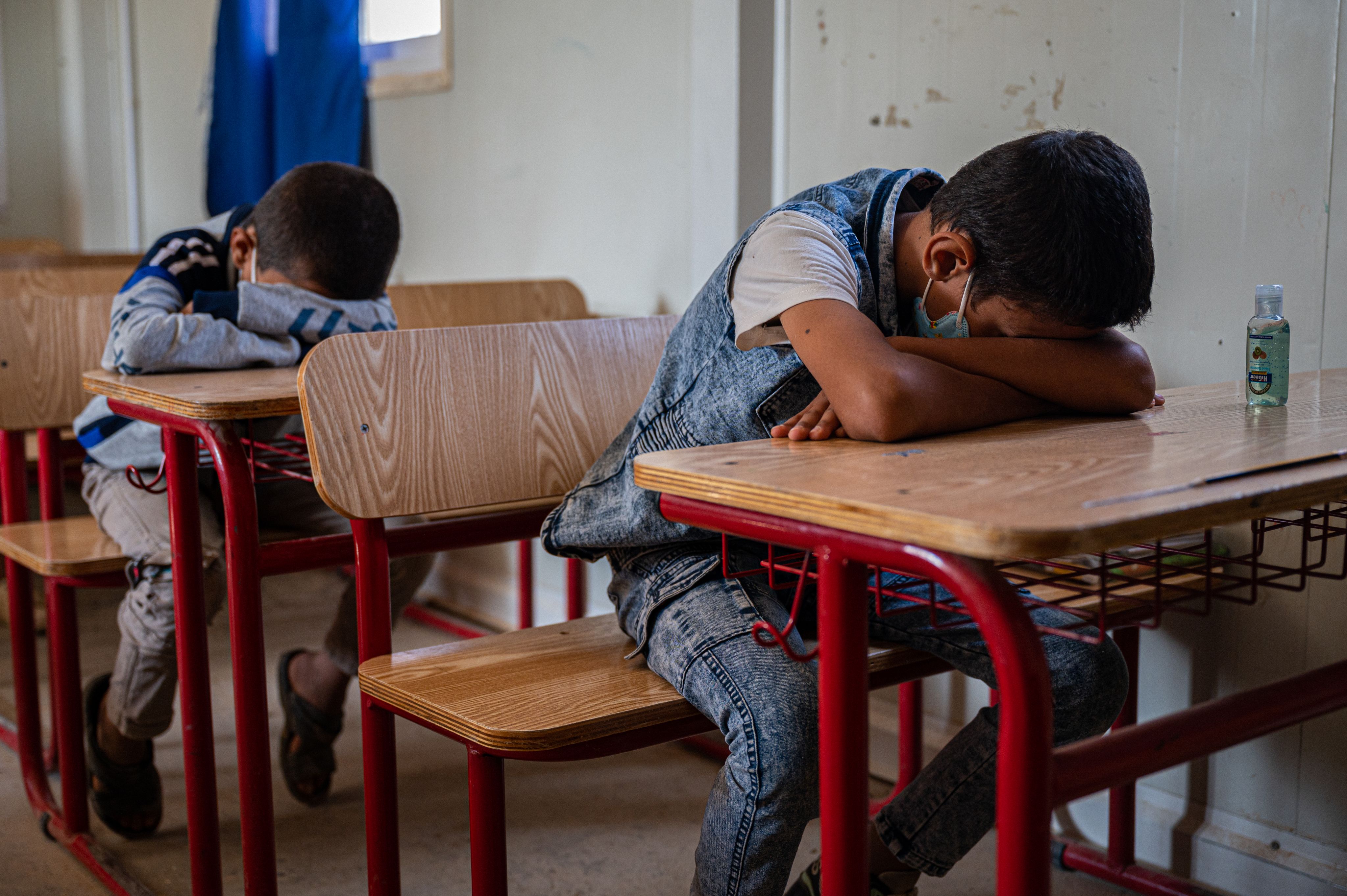 Syrian refugee children sit at their desks with their eyes closed as part of a psychosocial support exercise.