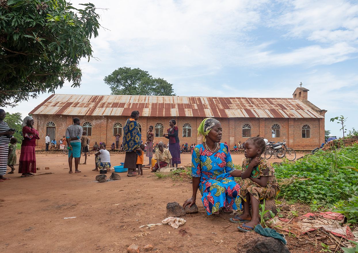 Woman and child sitting on the ground in front of a church.