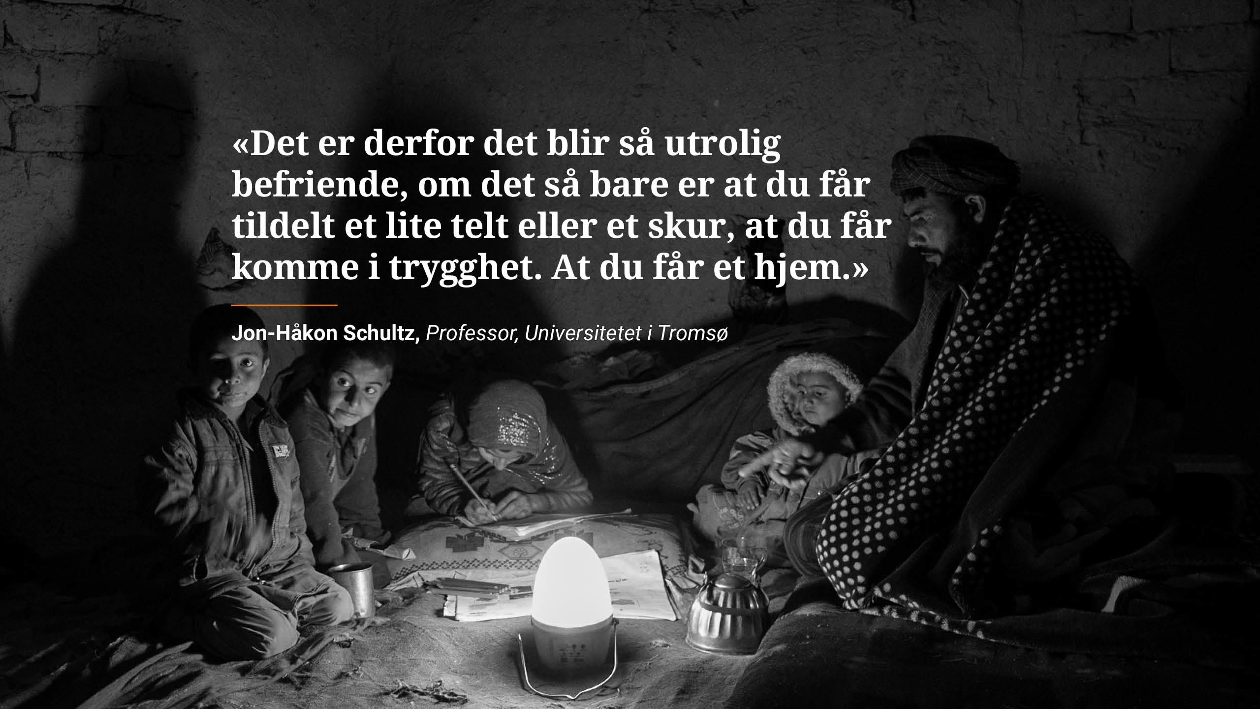 En far og hans fire barn sitter rundt en solcelledrevet lampe.