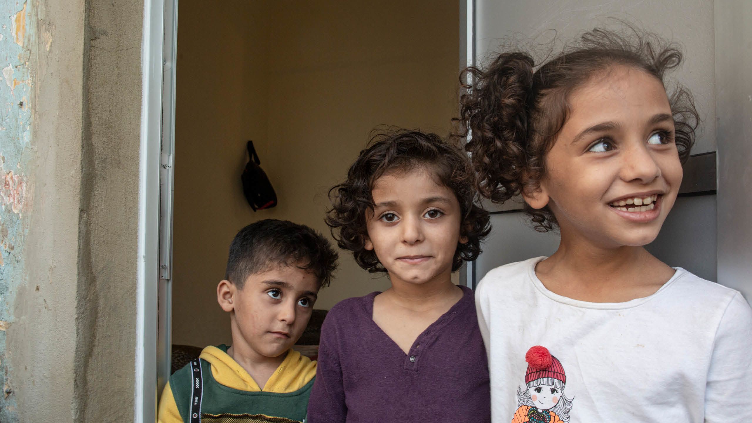 Søsknene Jude (6) og Fatima (7) står i døråpningen til leiligheten de bor i.