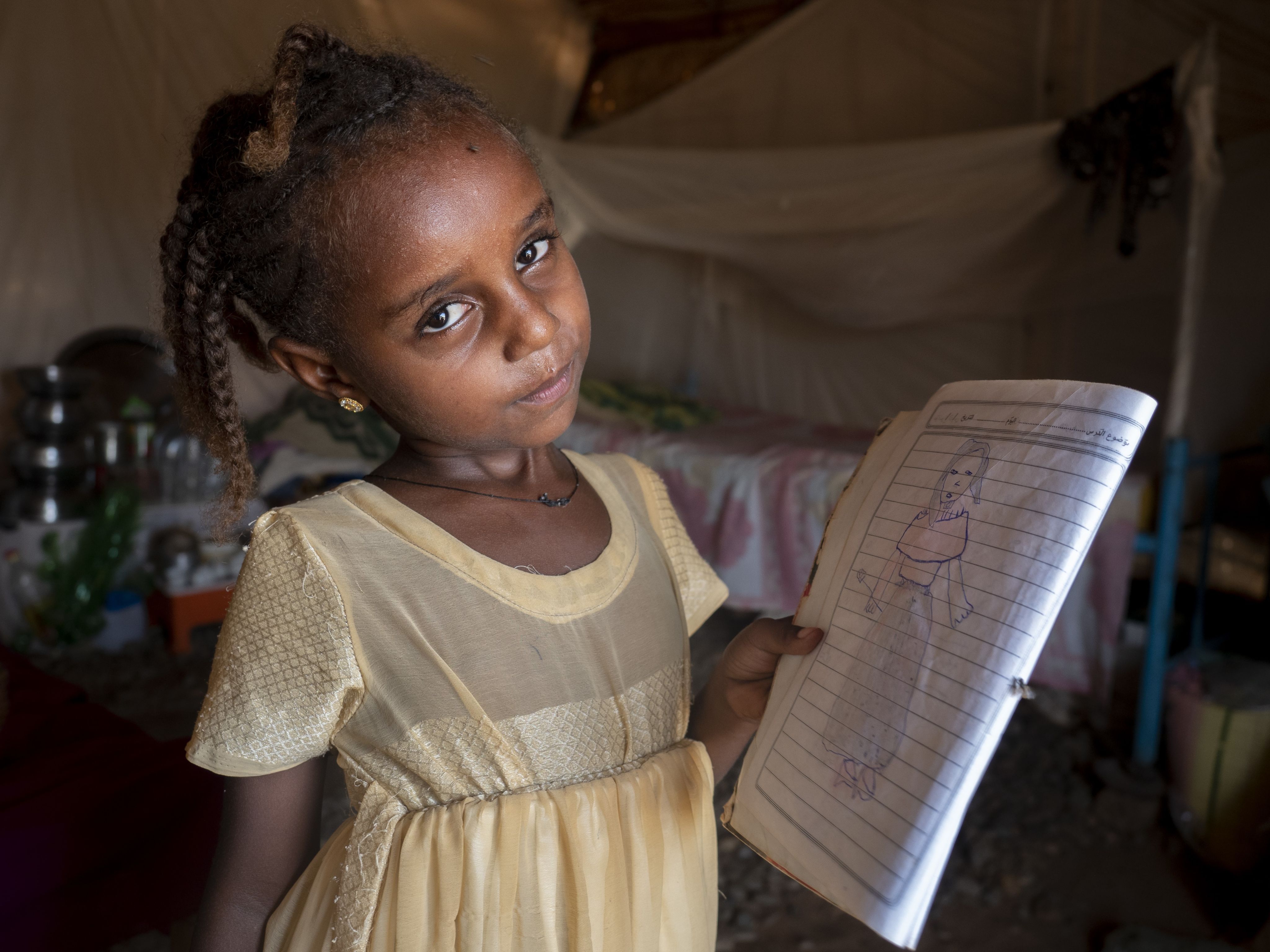 Melat, a young girl, shows a drawing she has done in her exercise book.