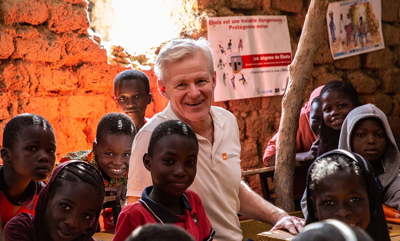 Jan Egeland sammen med en gruppe barneskoleelever. De smiler.